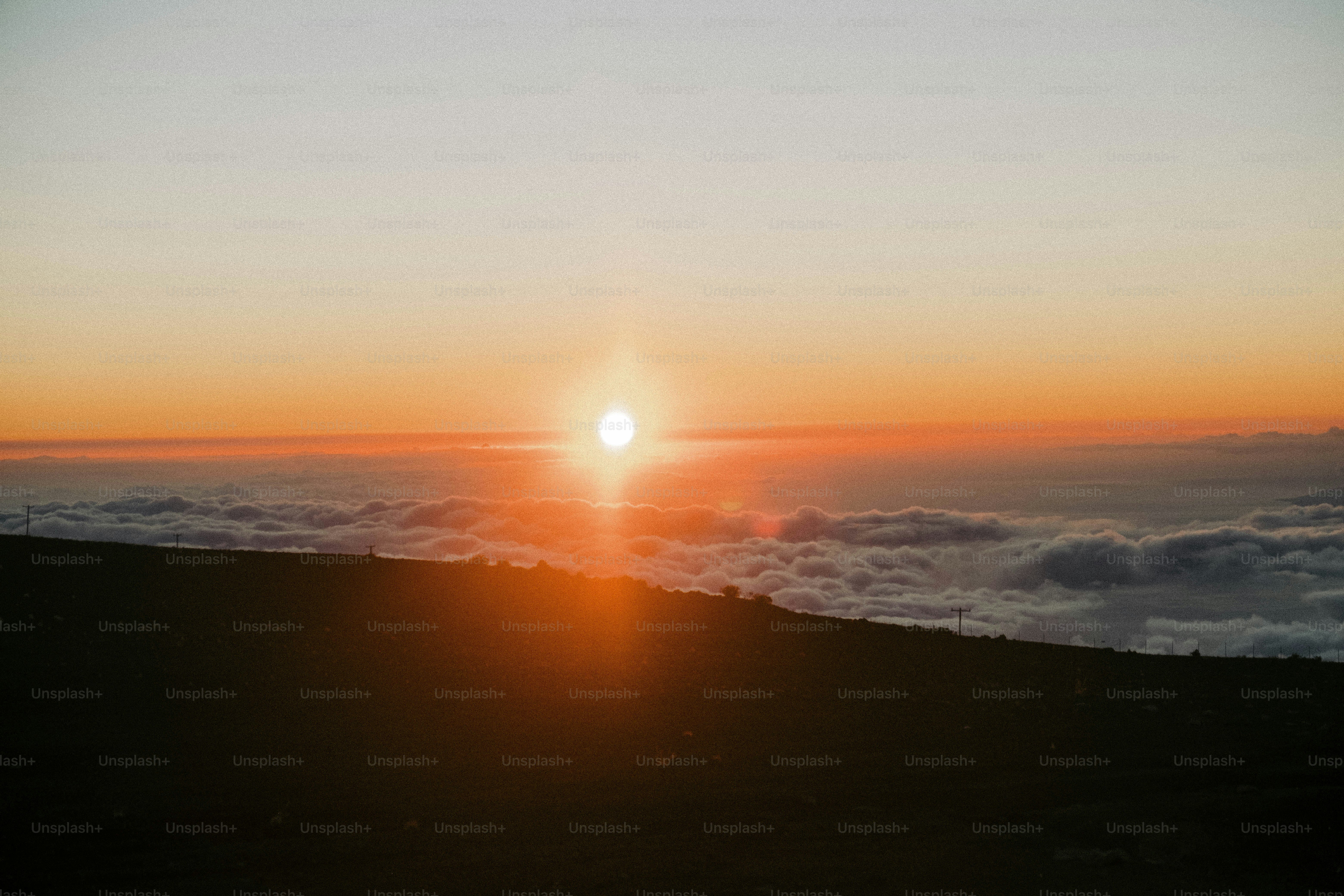 The sun is setting over the clouds in the sky