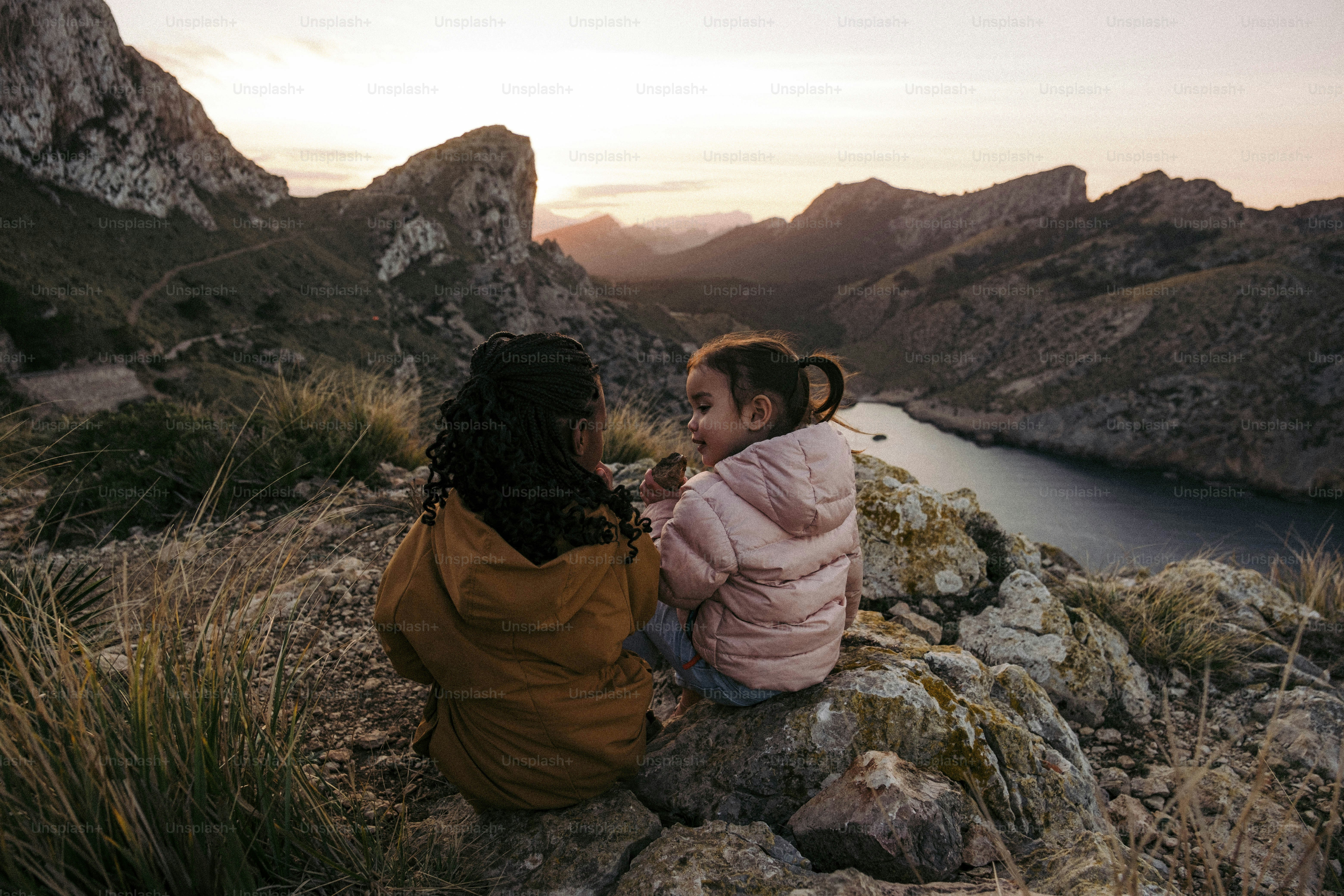 A couple of women sitting on top of a rocky hillside