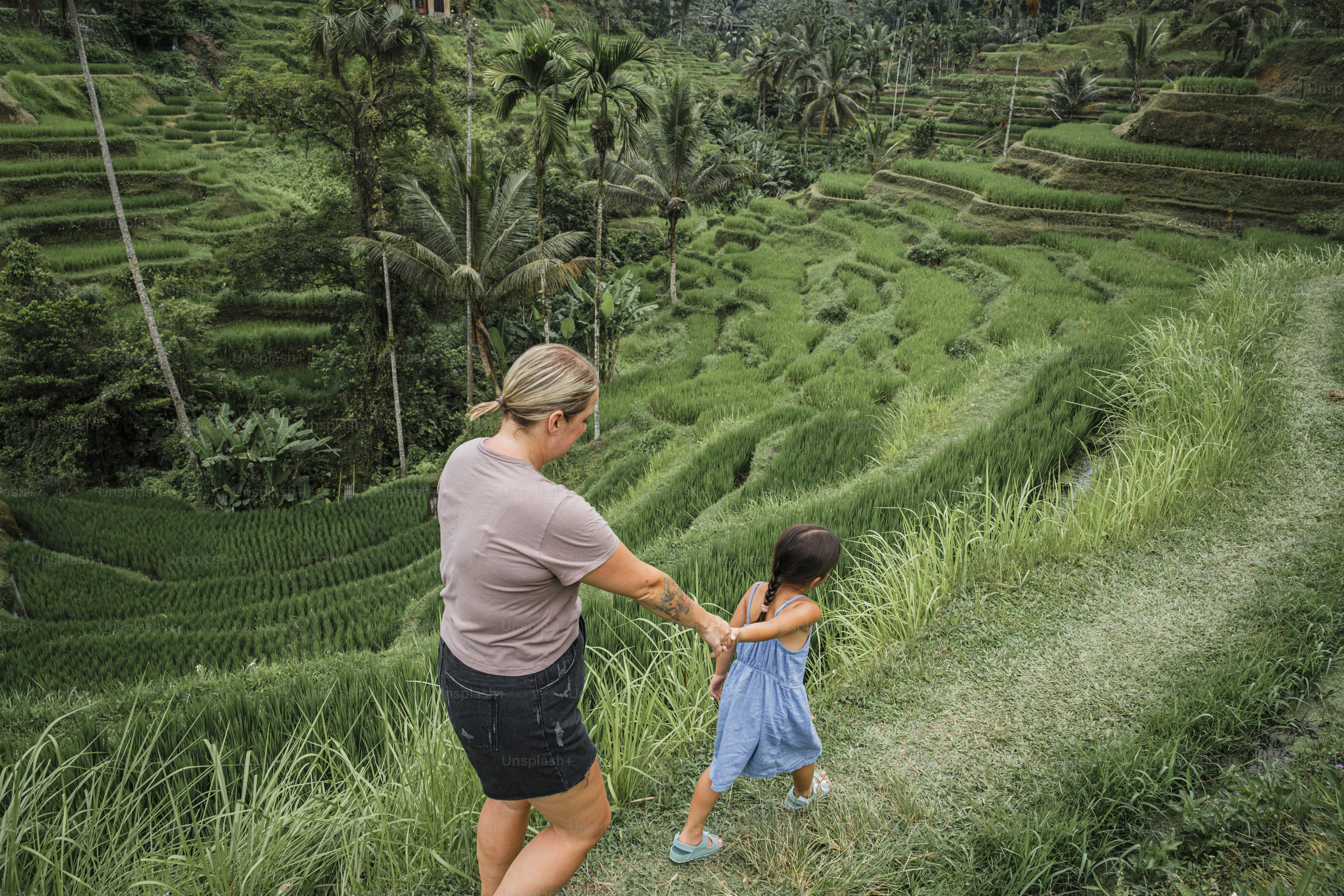 A woman holding the hand of a little girl in a field