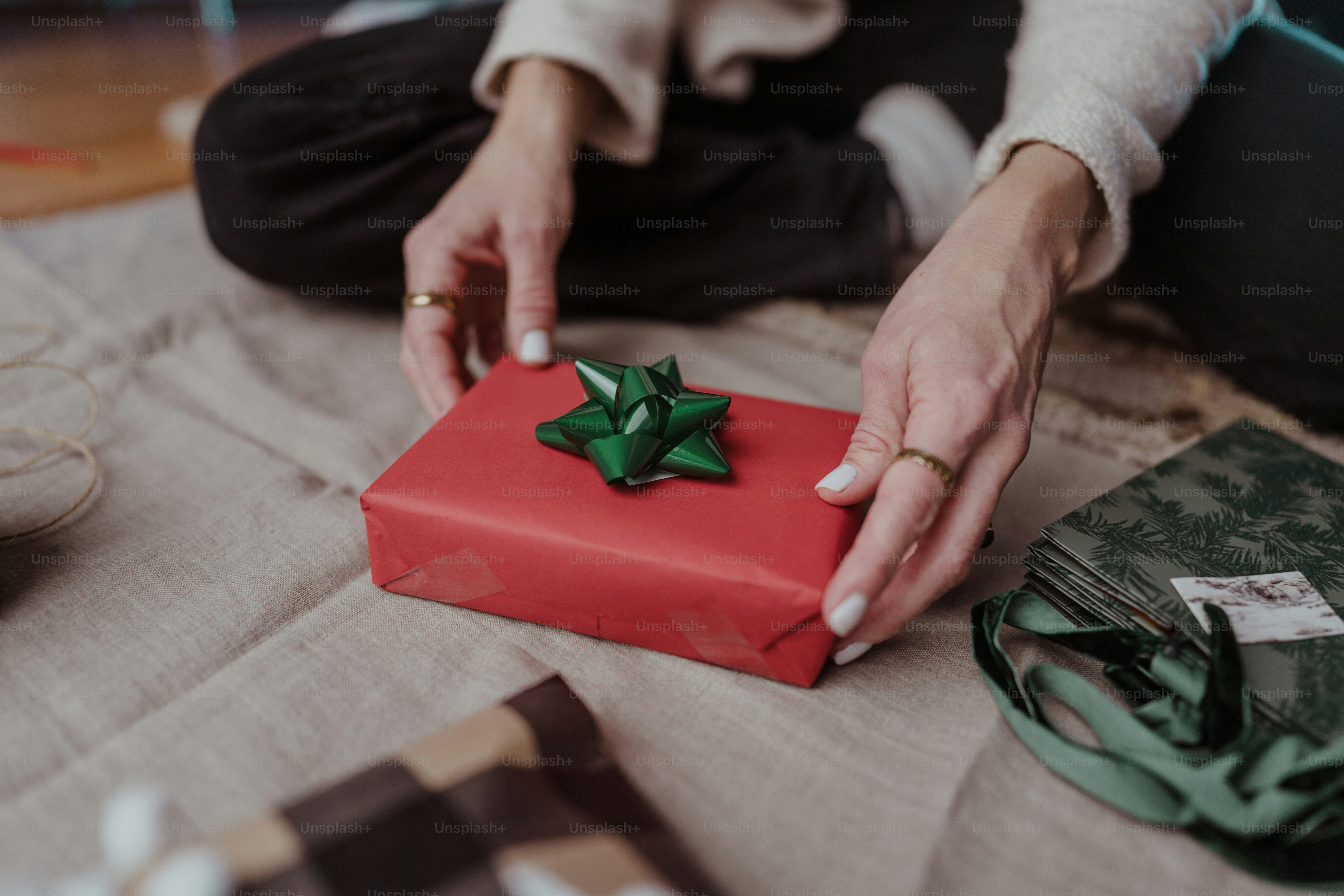 A woman holding a red present box with a green bow