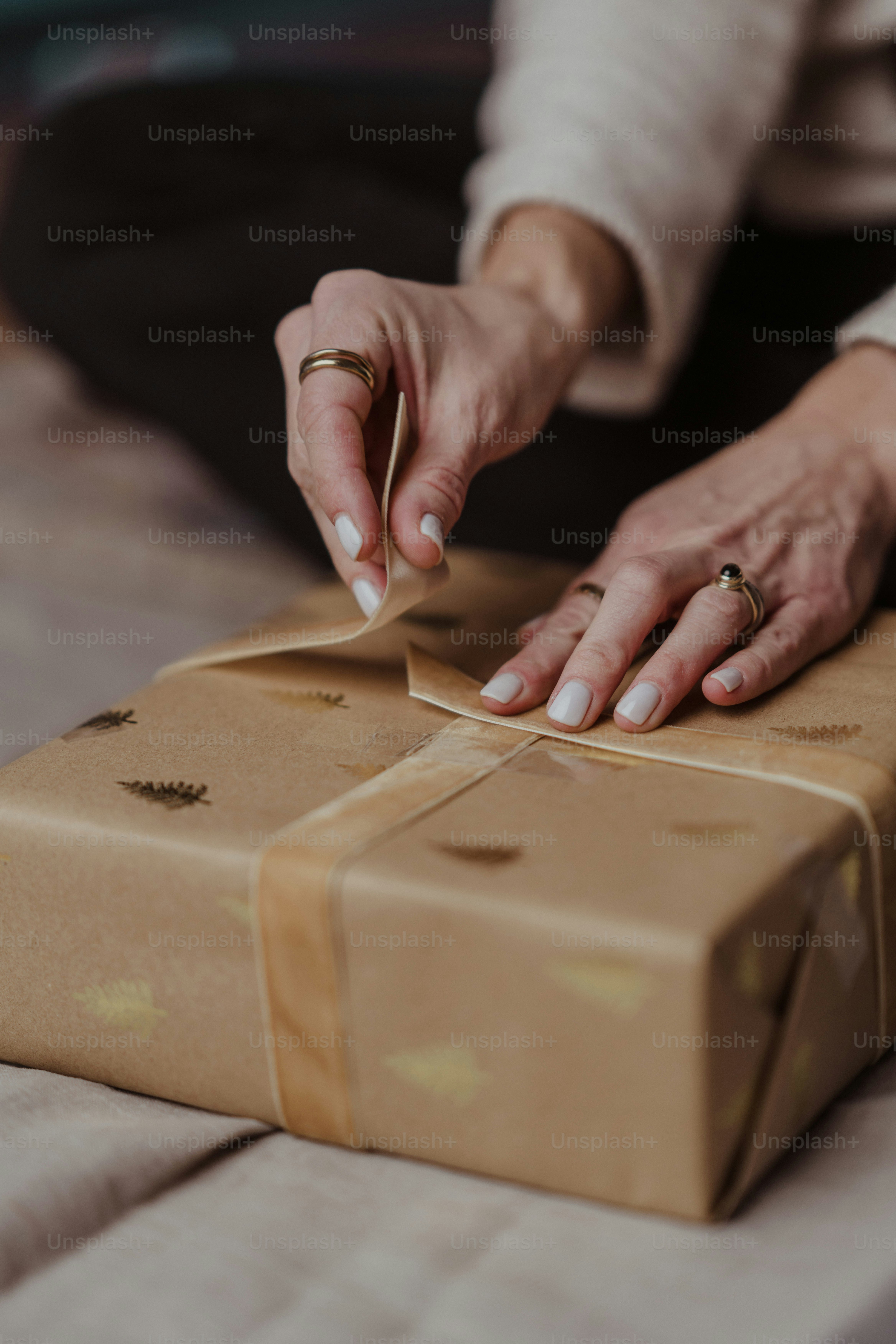 A woman is wrapping a brown box on a bed