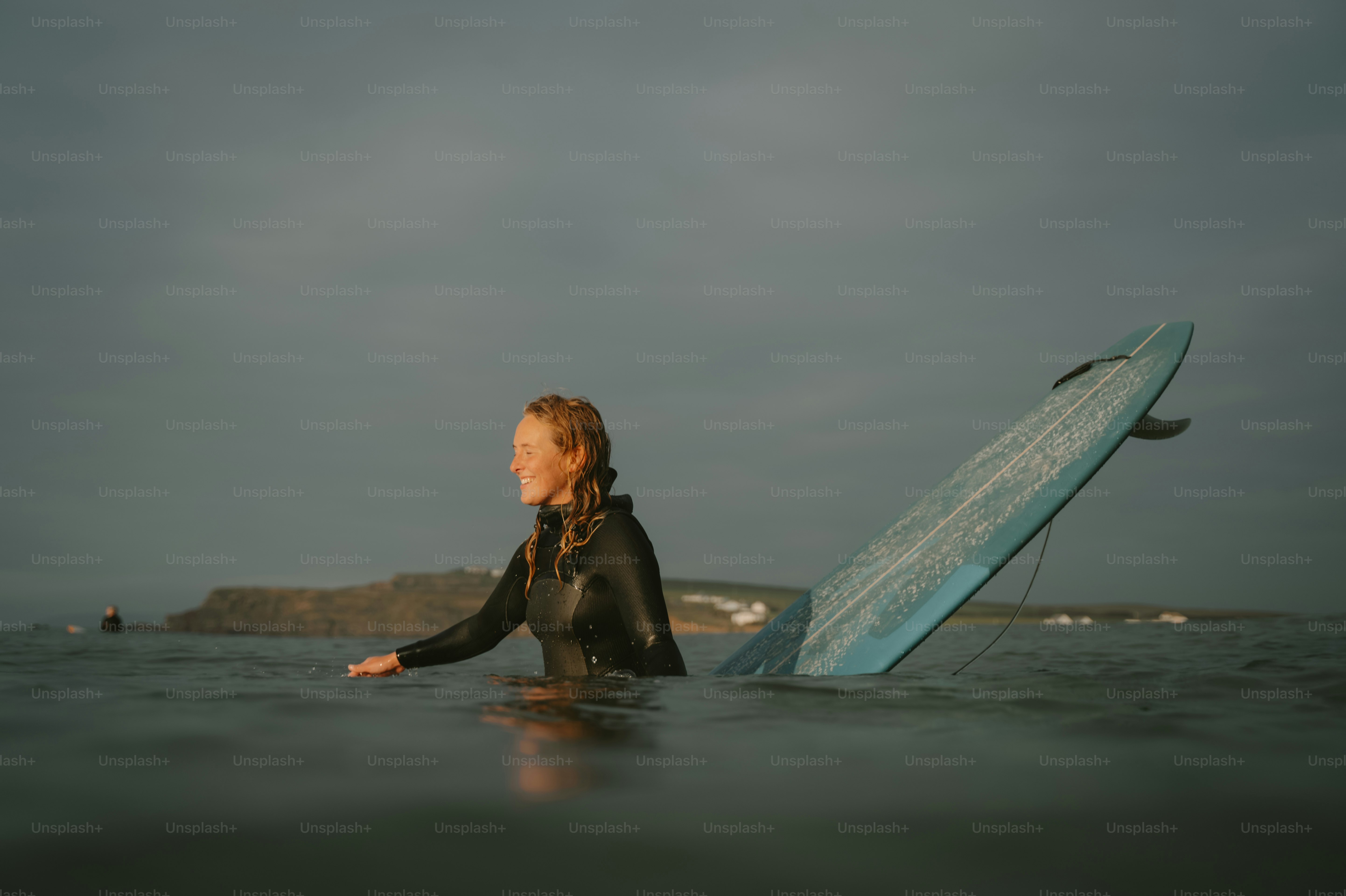 A woman in a wet suit holding a surfboard in the ocean