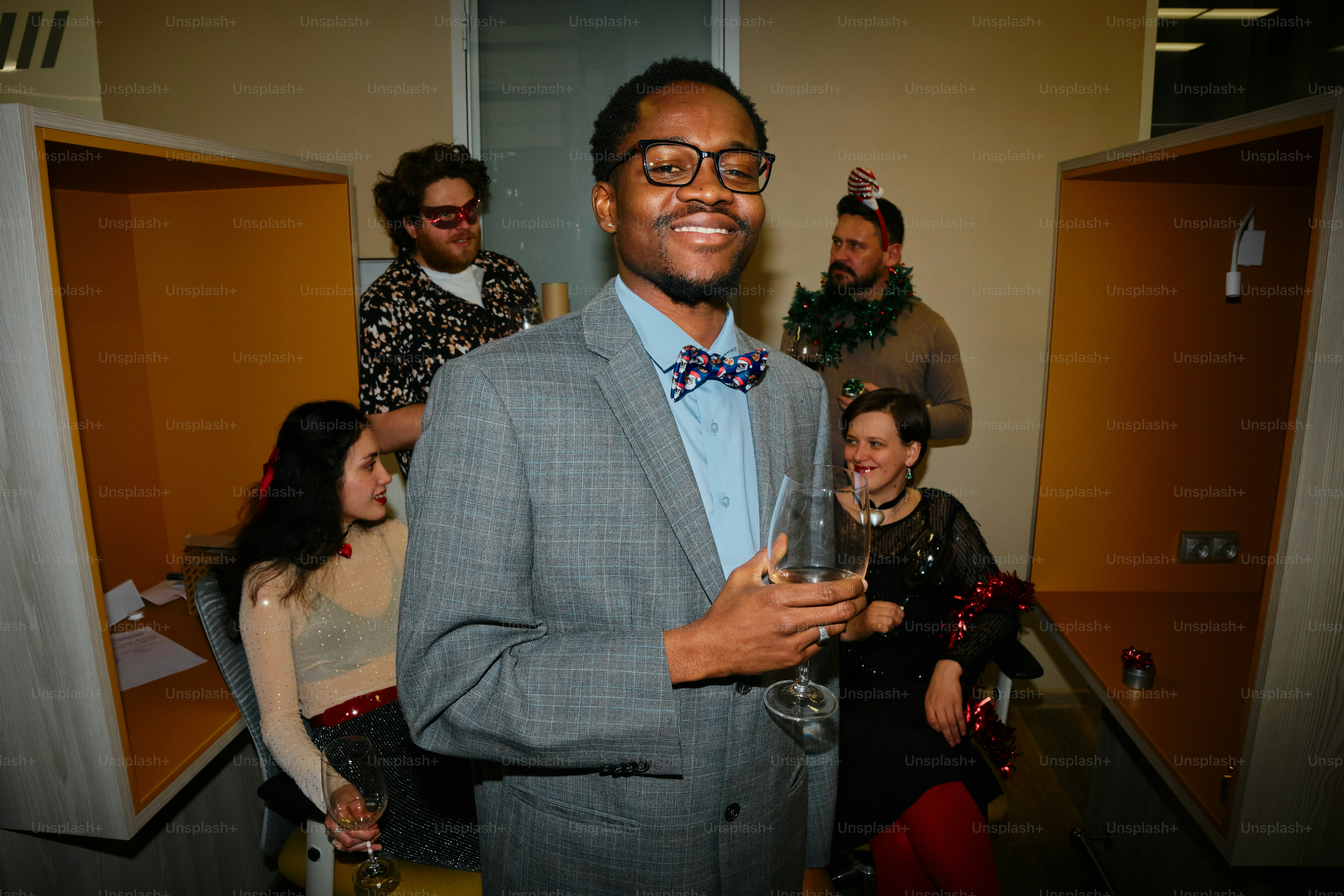 A man in a suit and bow tie holding a glass of wine