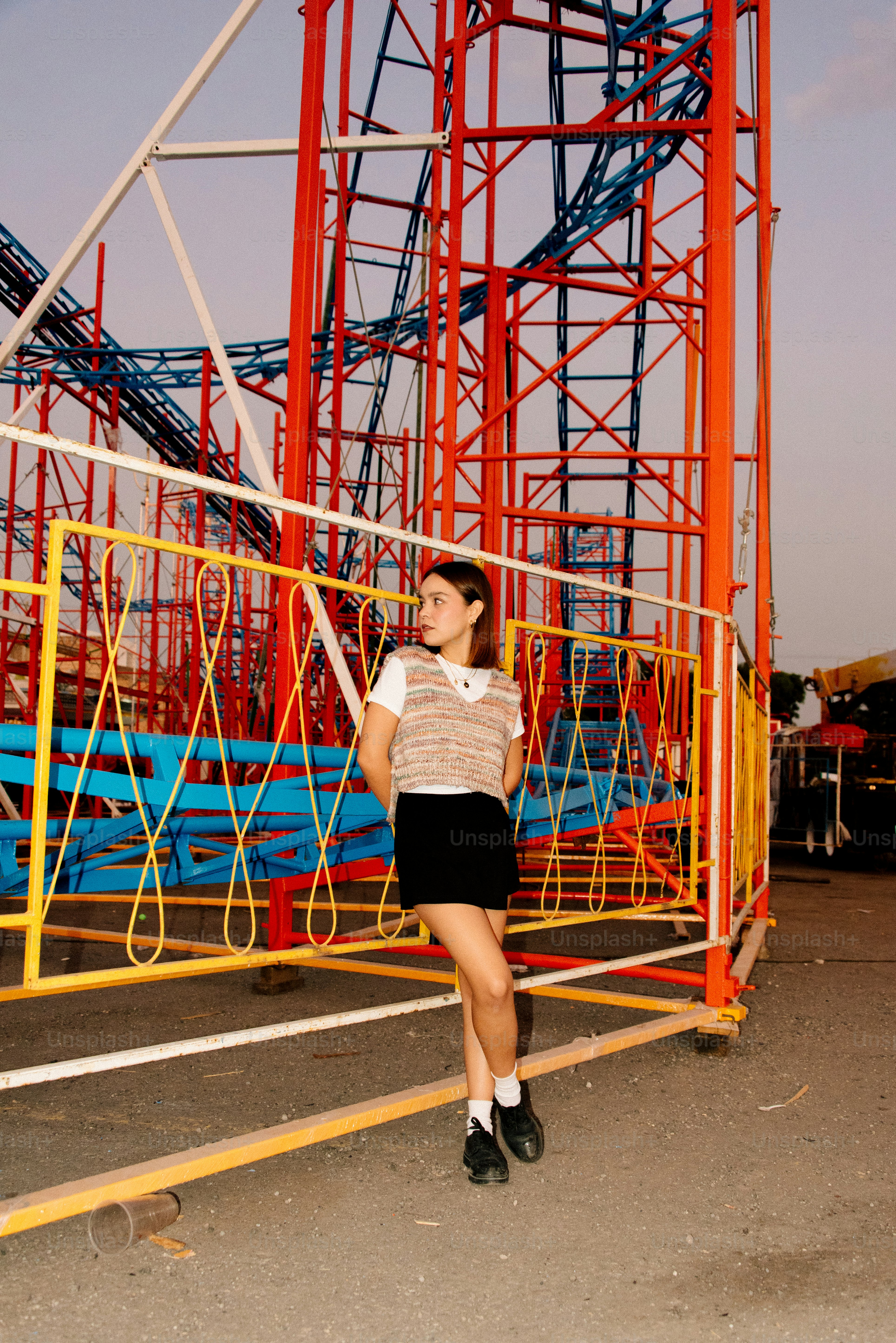 A woman standing in front of a roller coaster