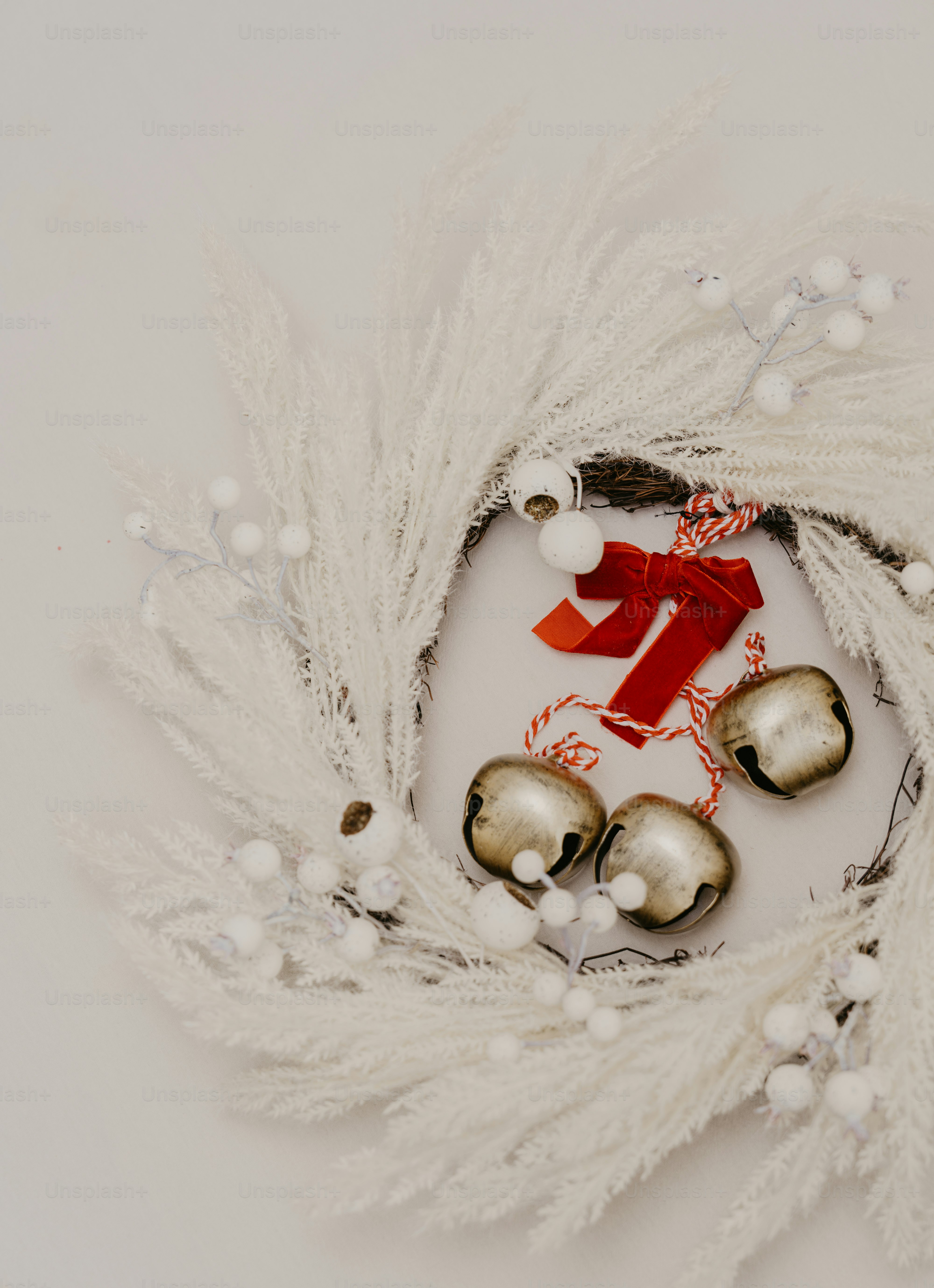 A white wreath with bells and a red ribbon