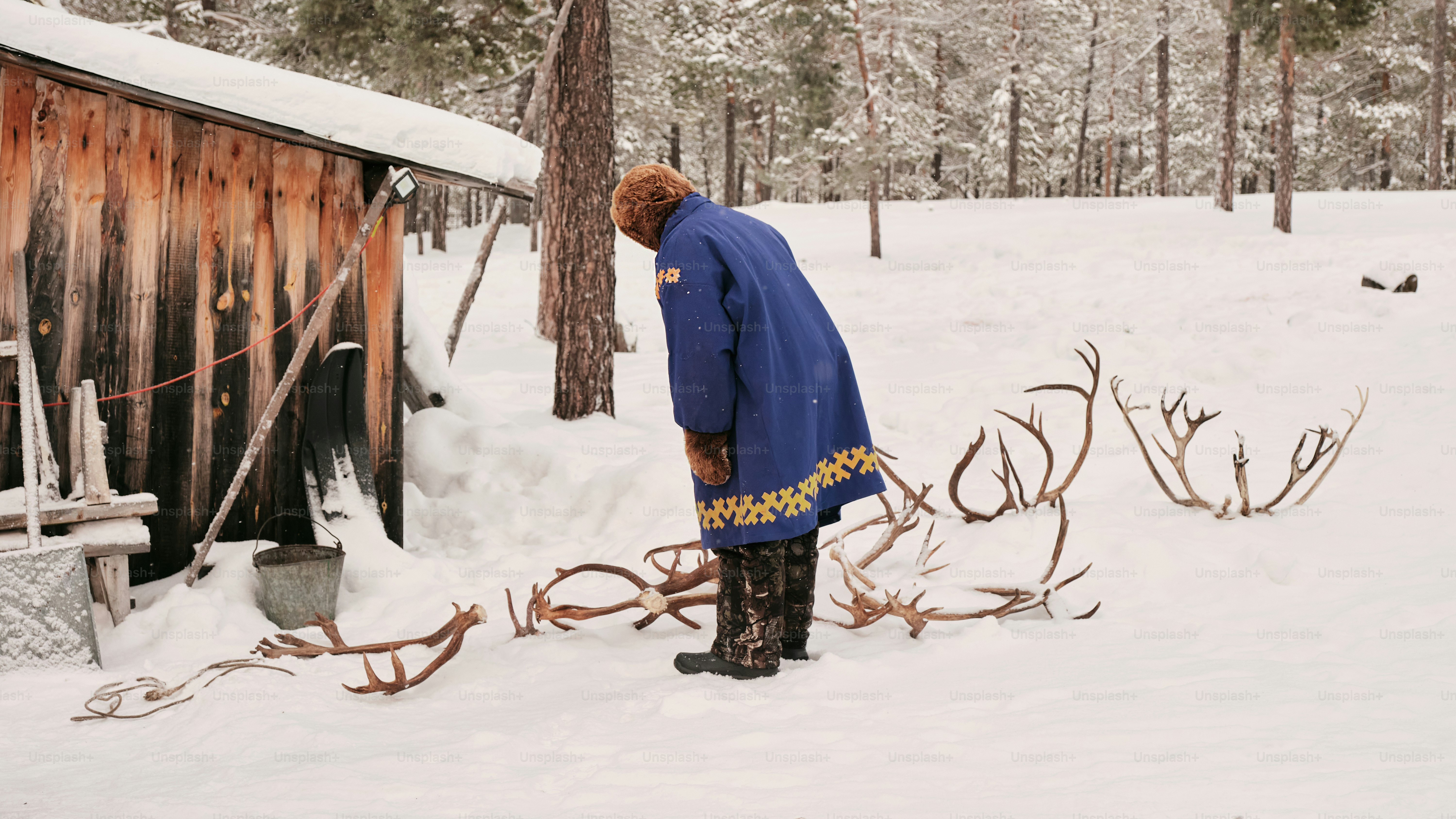 A man standing in the snow next to a shack