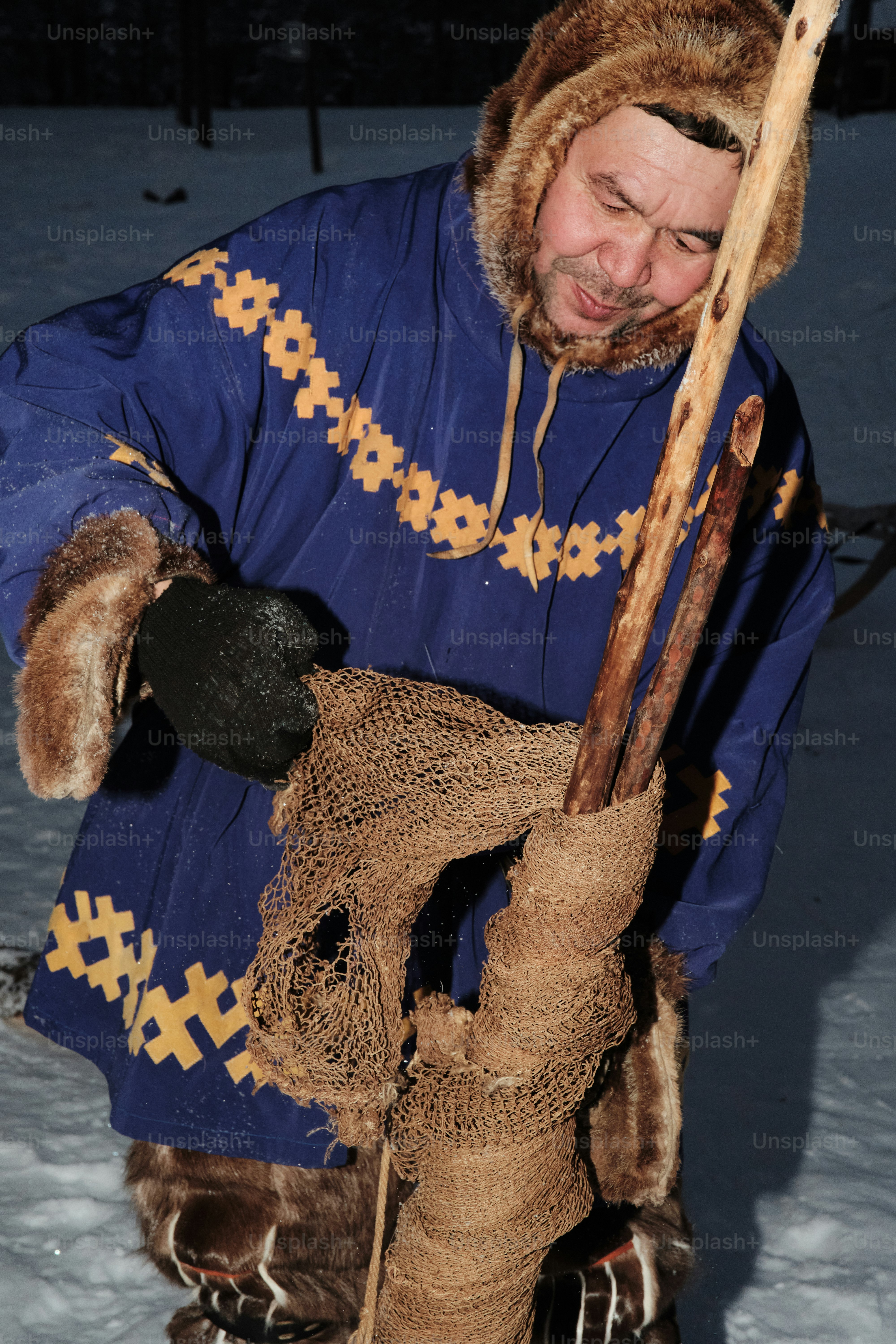 A man in a blue coat holding a wooden stick