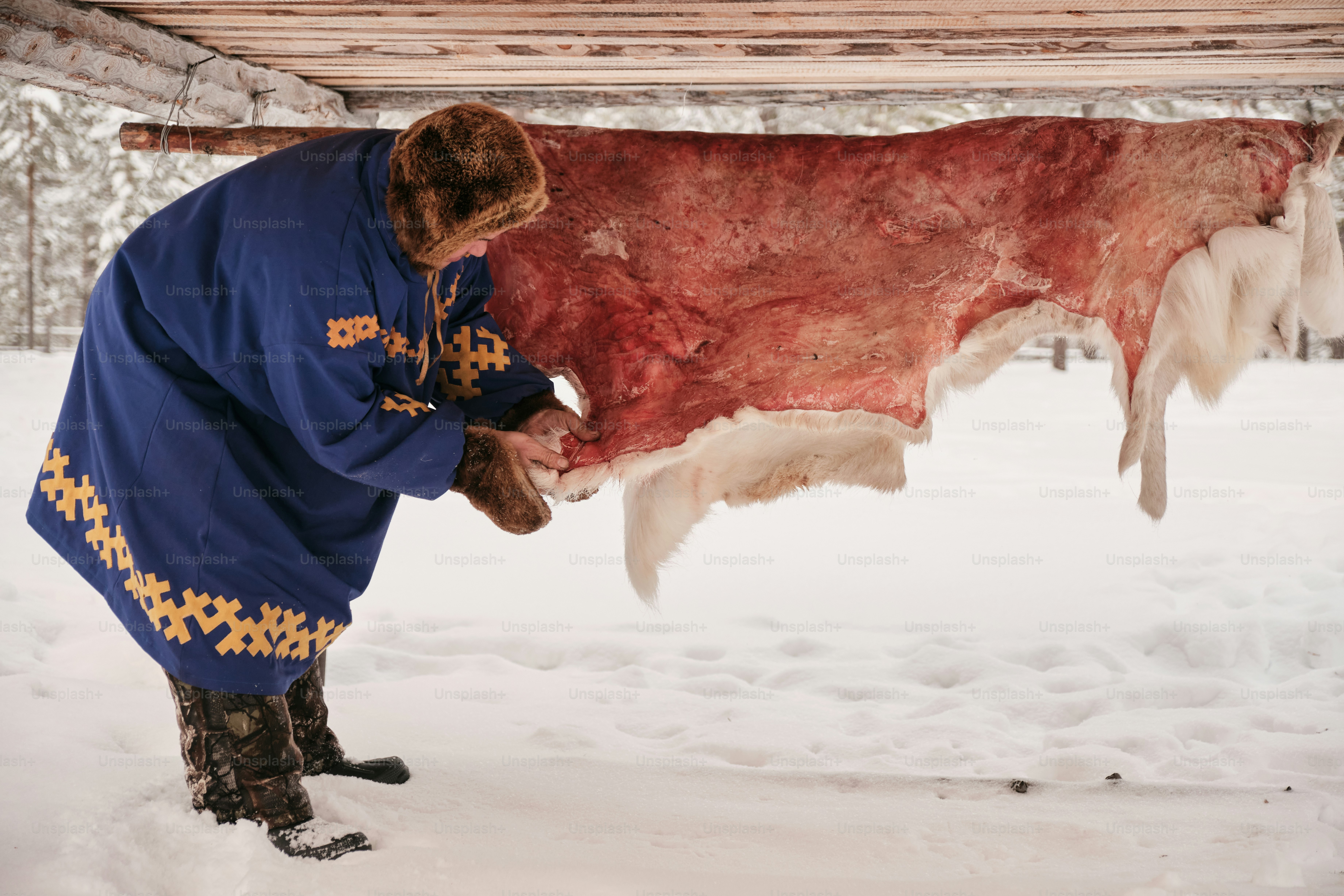 A man in a blue coat holding a large piece of meat