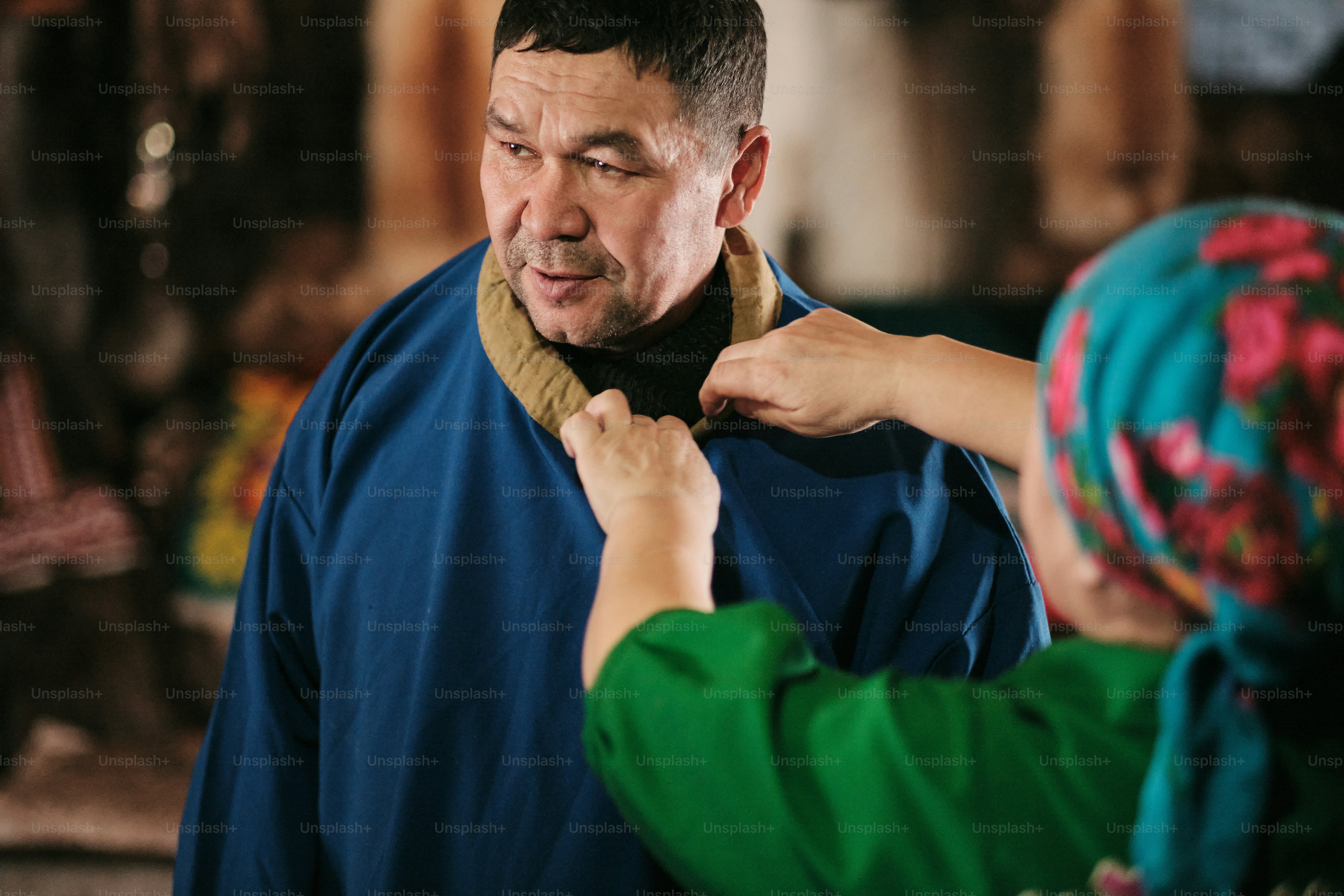 A man helping a woman put on a scarf