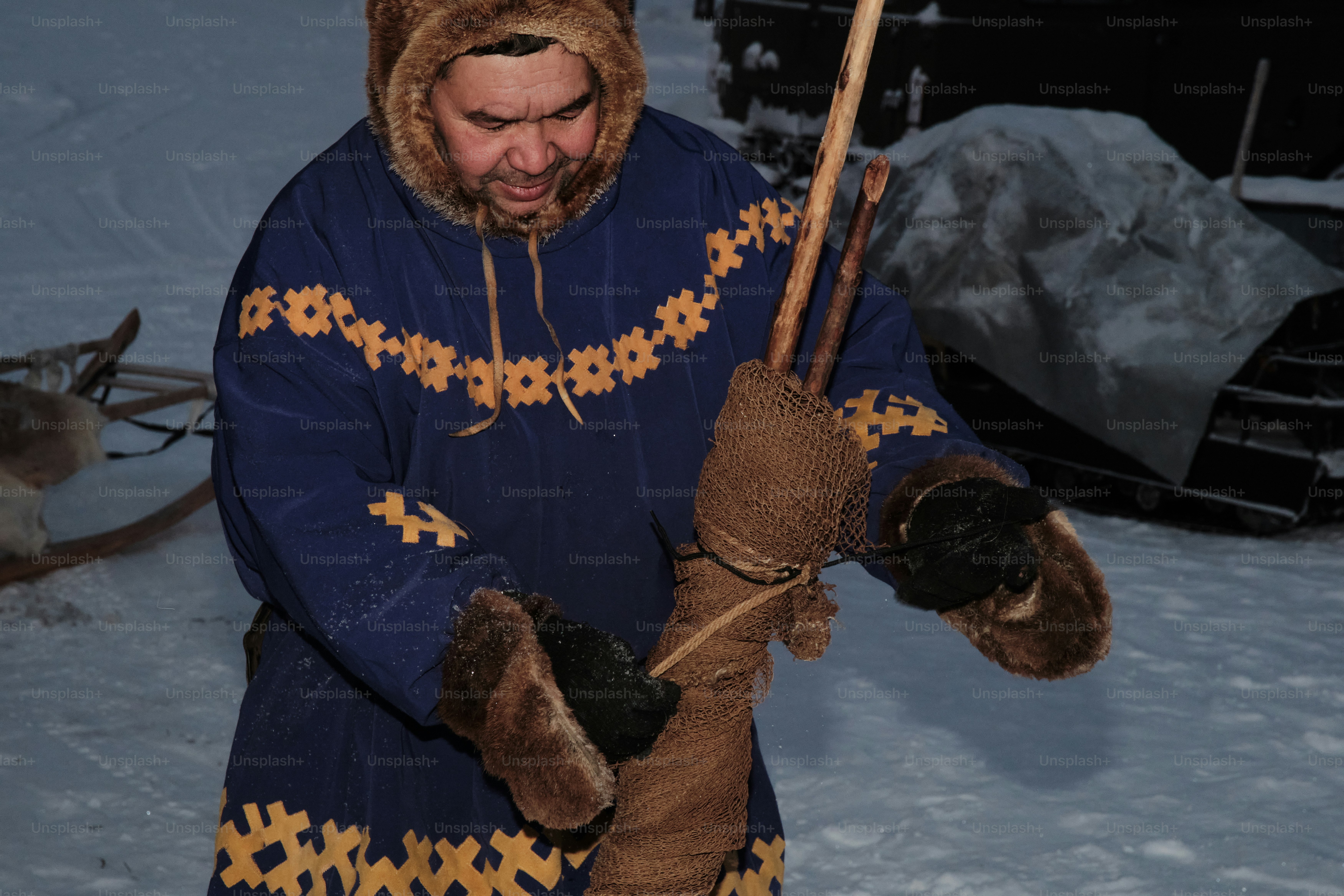 A man in a blue coat holding a stick in the snow