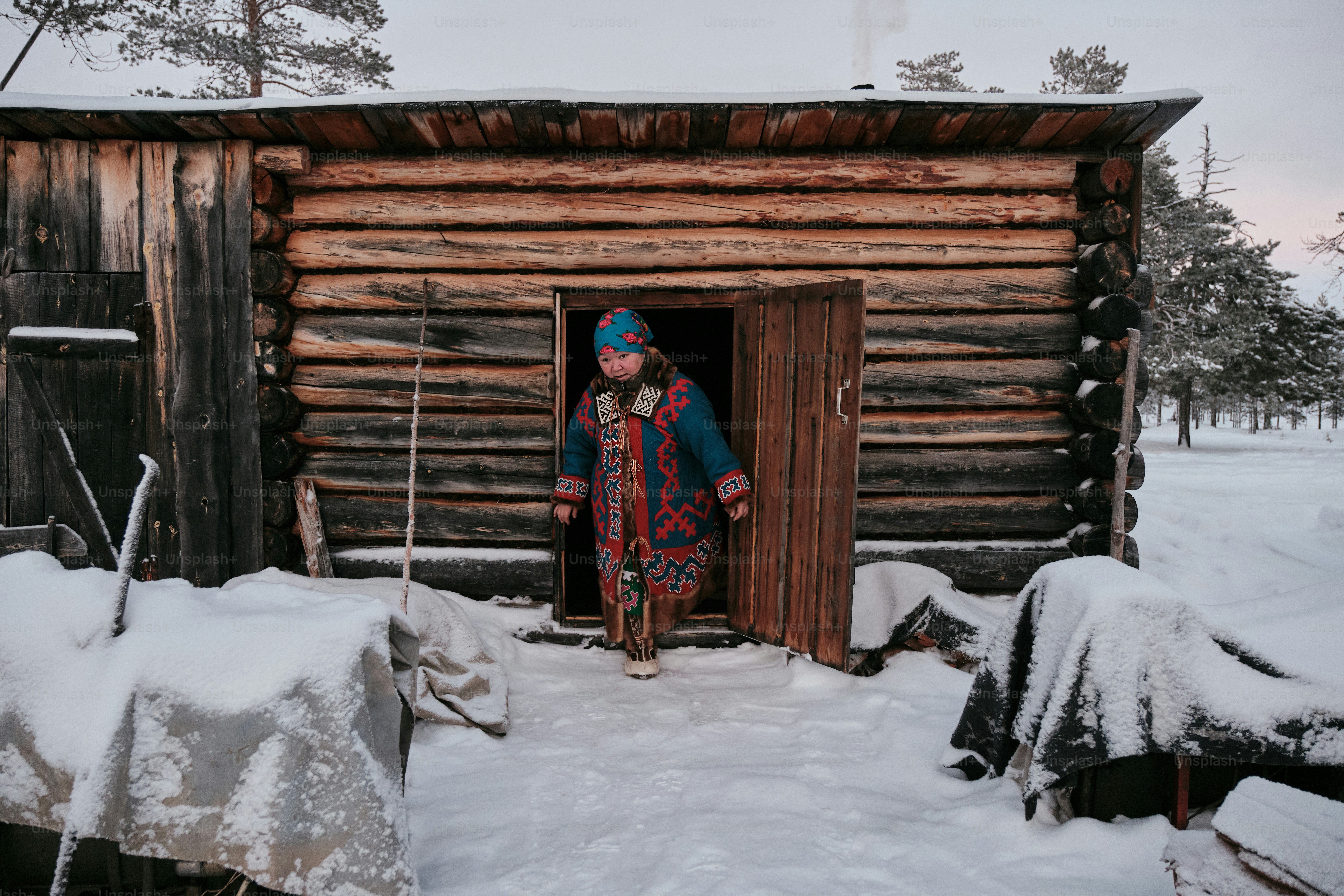 A person standing outside of a cabin in the snow