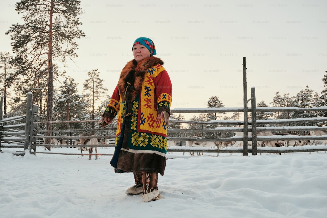 A woman standing in the snow in front of a fence