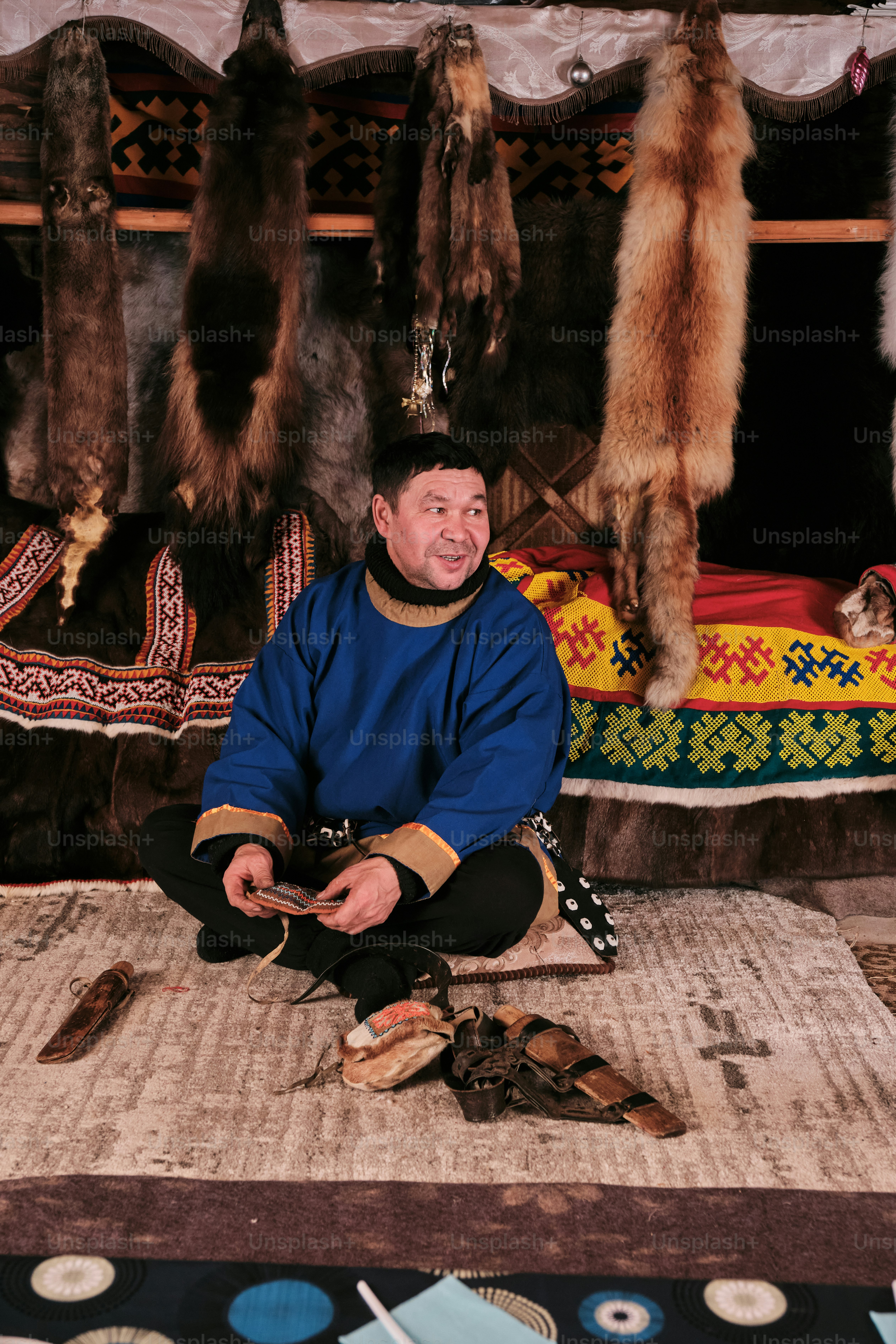 A man sitting on the ground in front of a rug