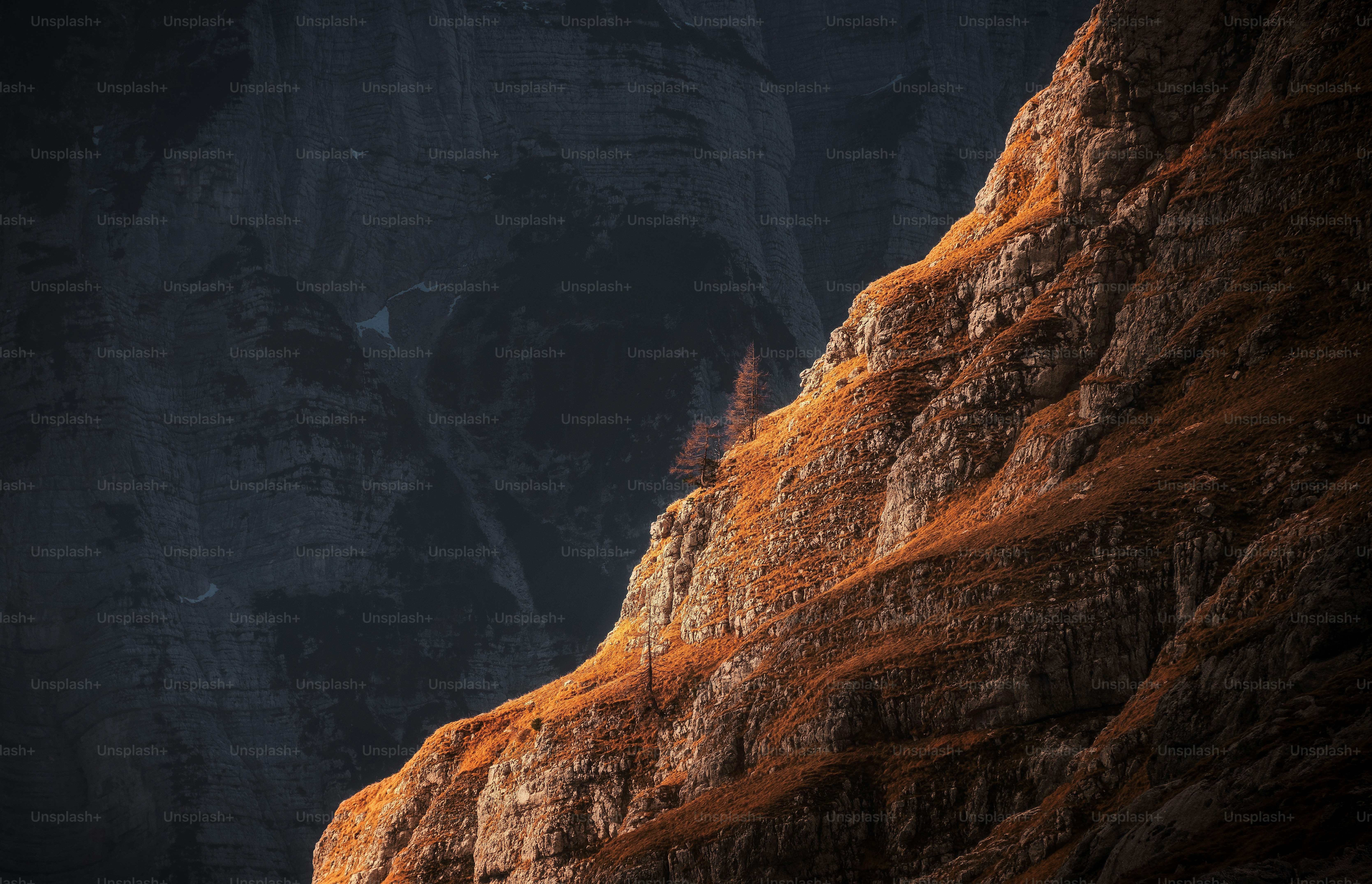 A man standing on top of a cliff next to a mountain
