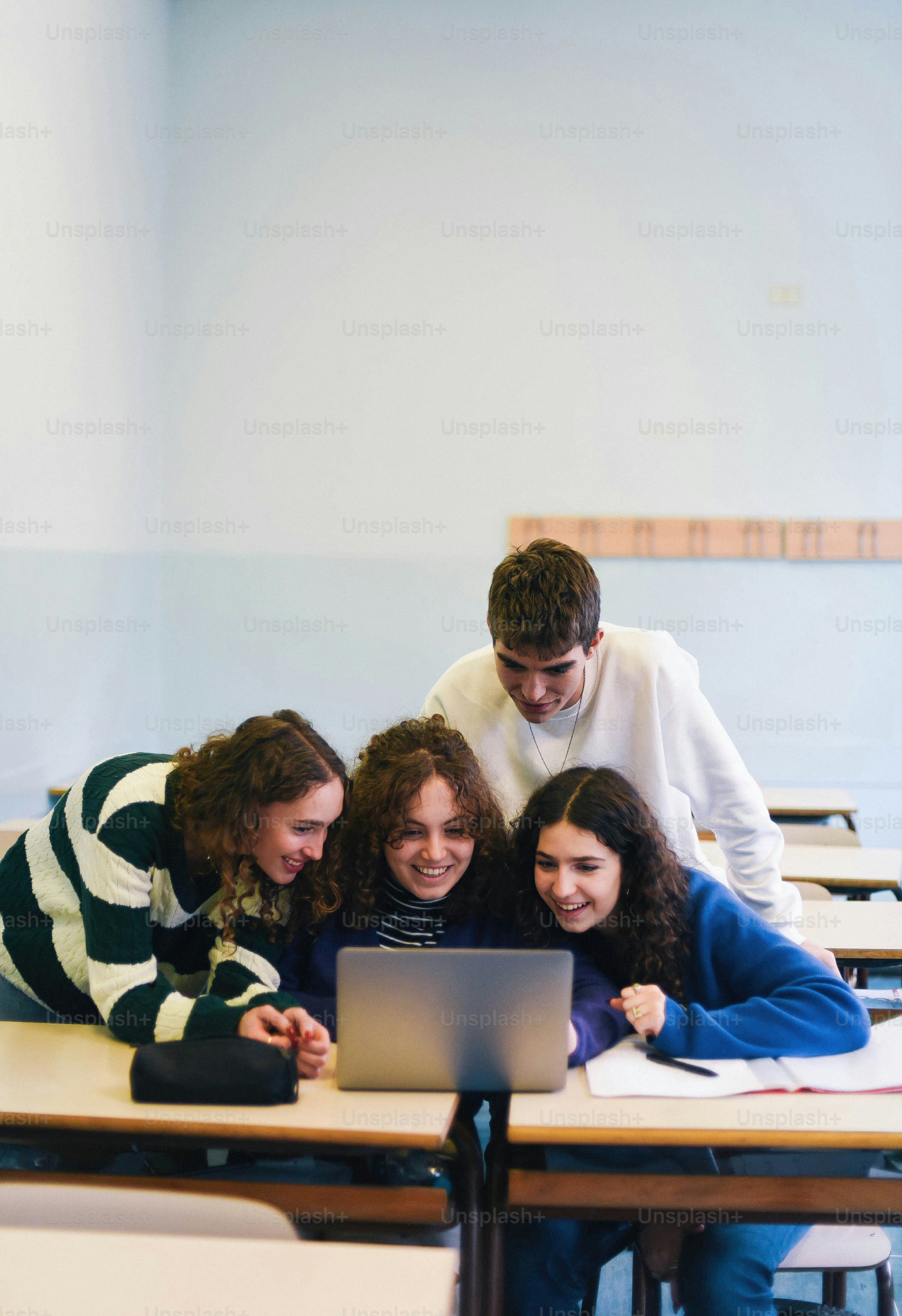 A group of people sitting around a laptop computer