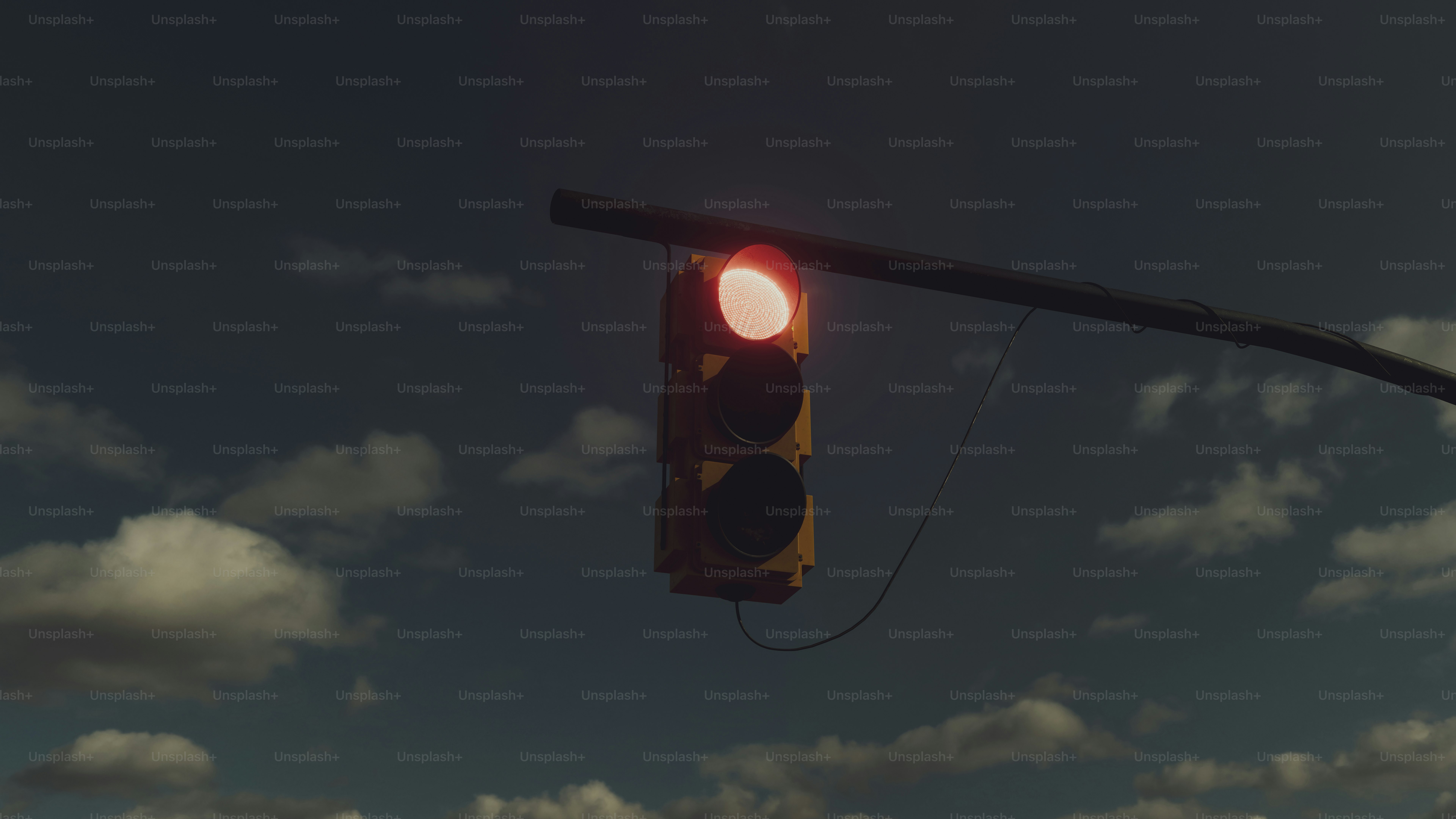 A traffic light on a pole with clouds in the background