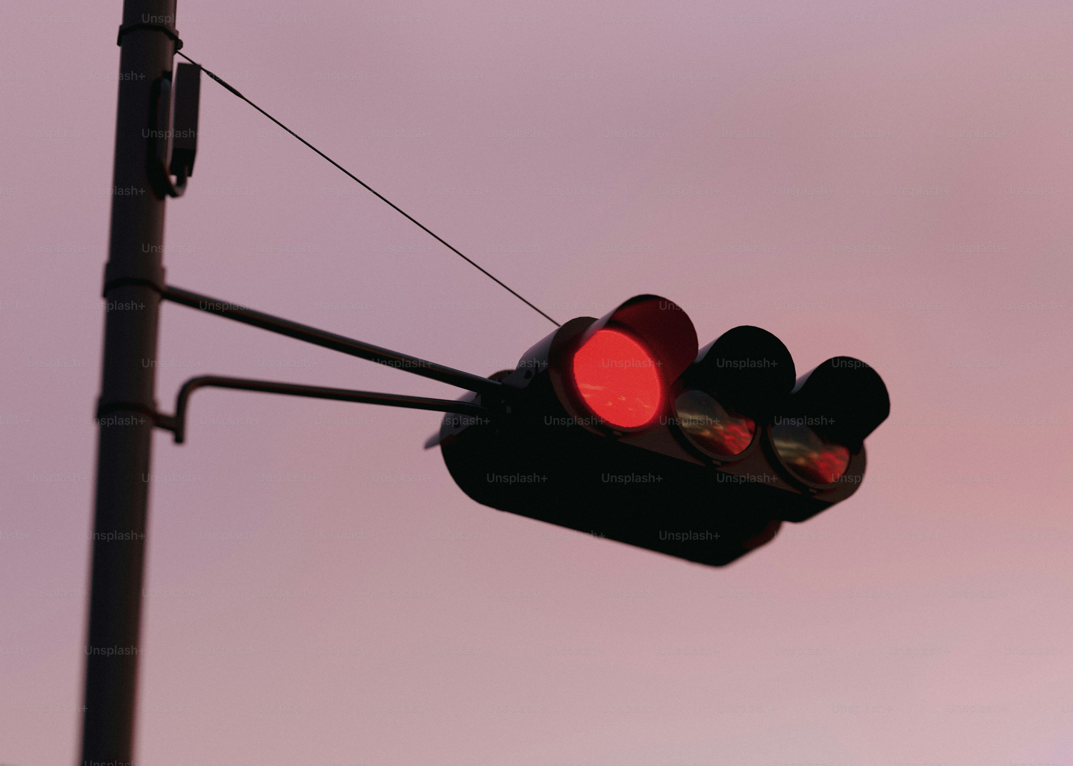 A traffic light with a red light hanging off of it's side