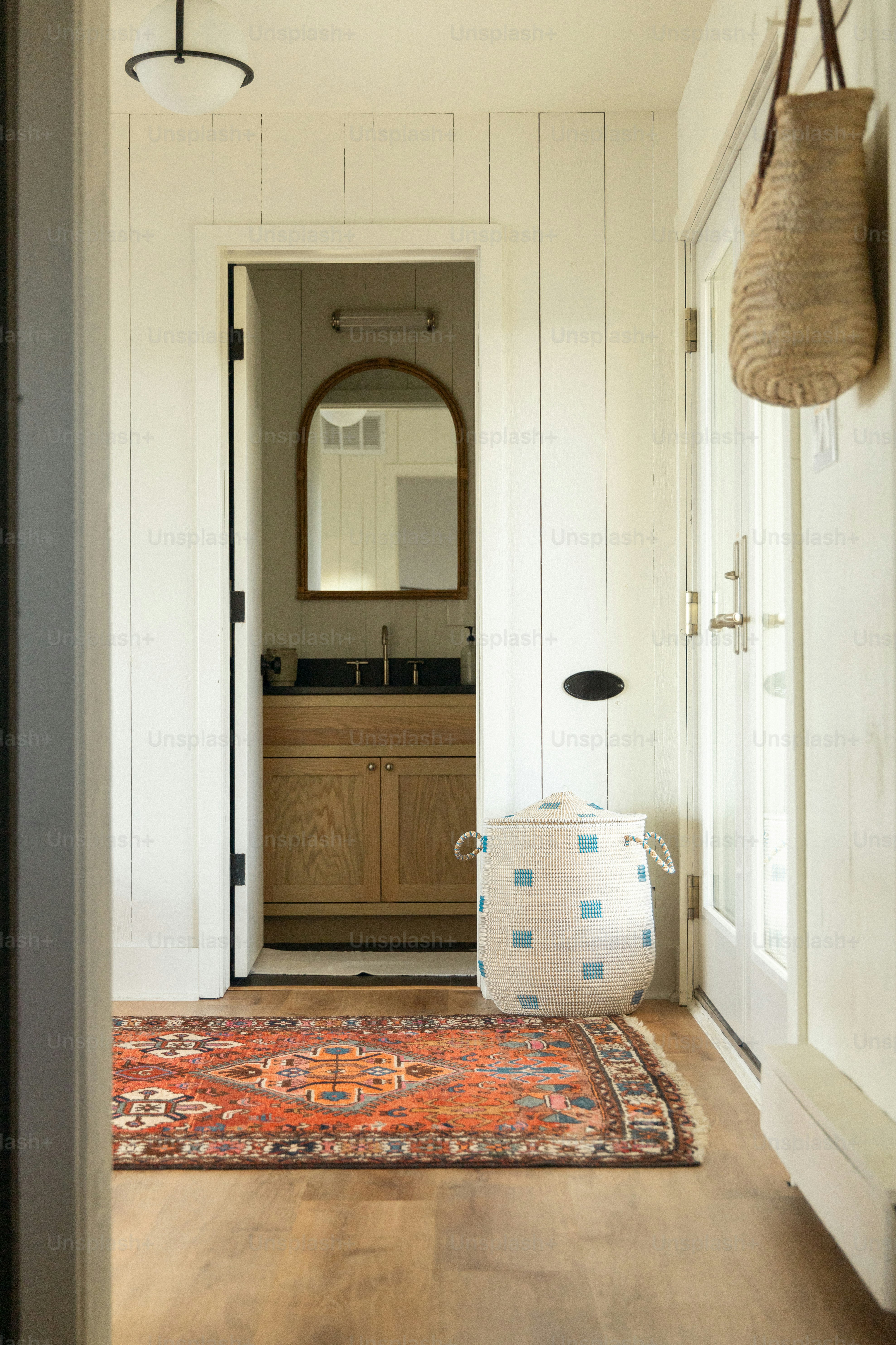 A hallway leading to a bathroom with a rug on the floor
