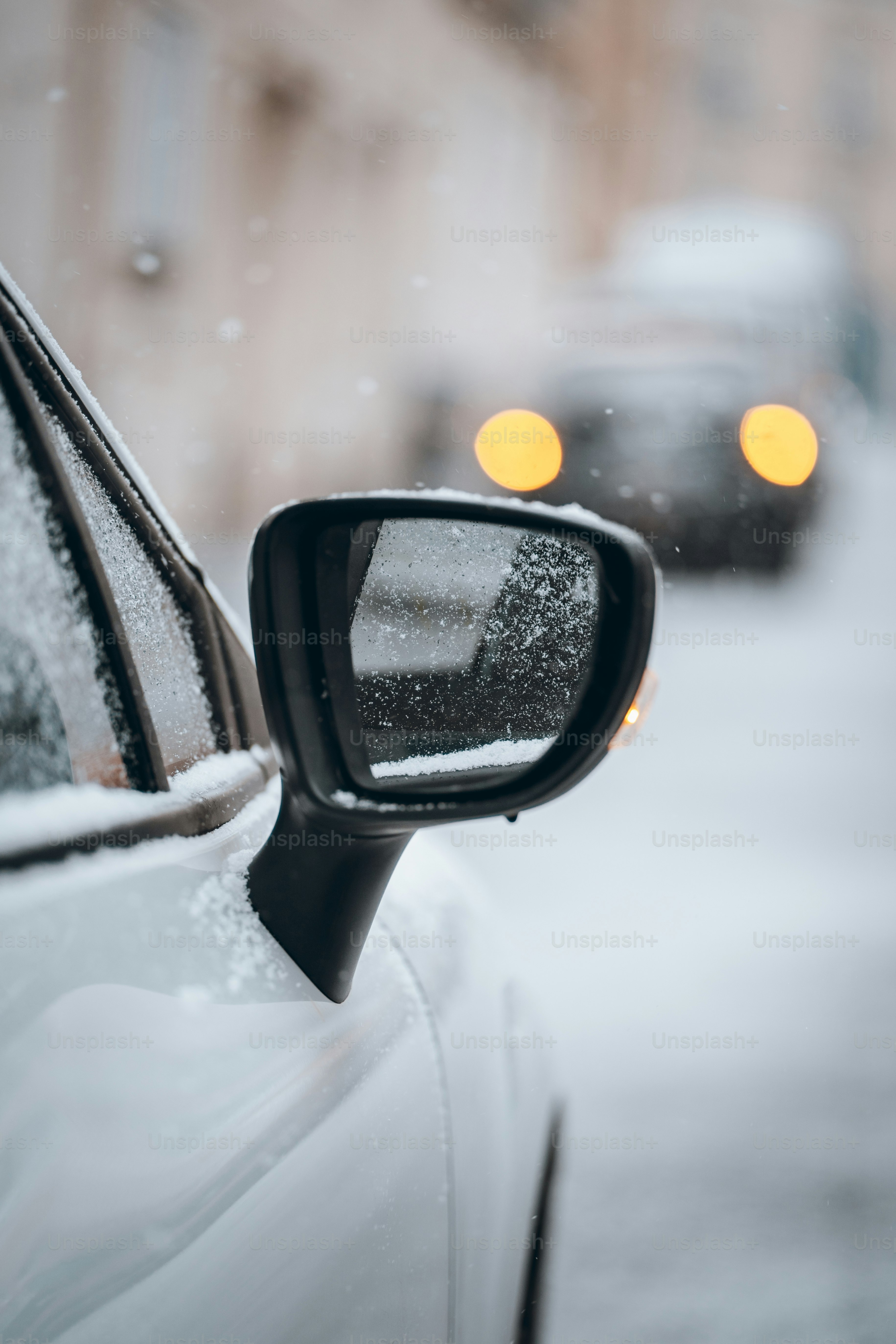 A rear view mirror of a car on a snowy street
