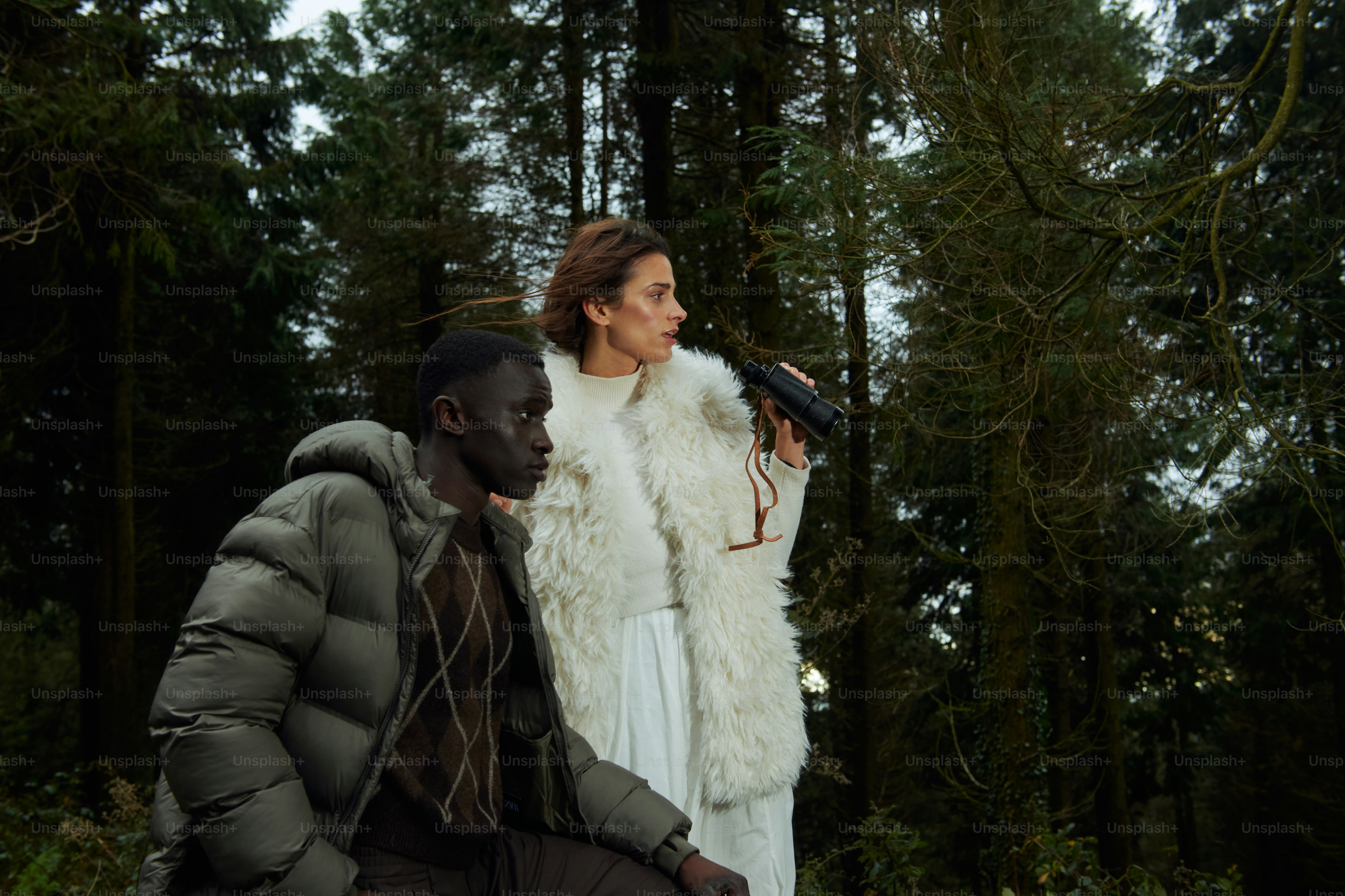 A man and a woman standing next to each other in the woods