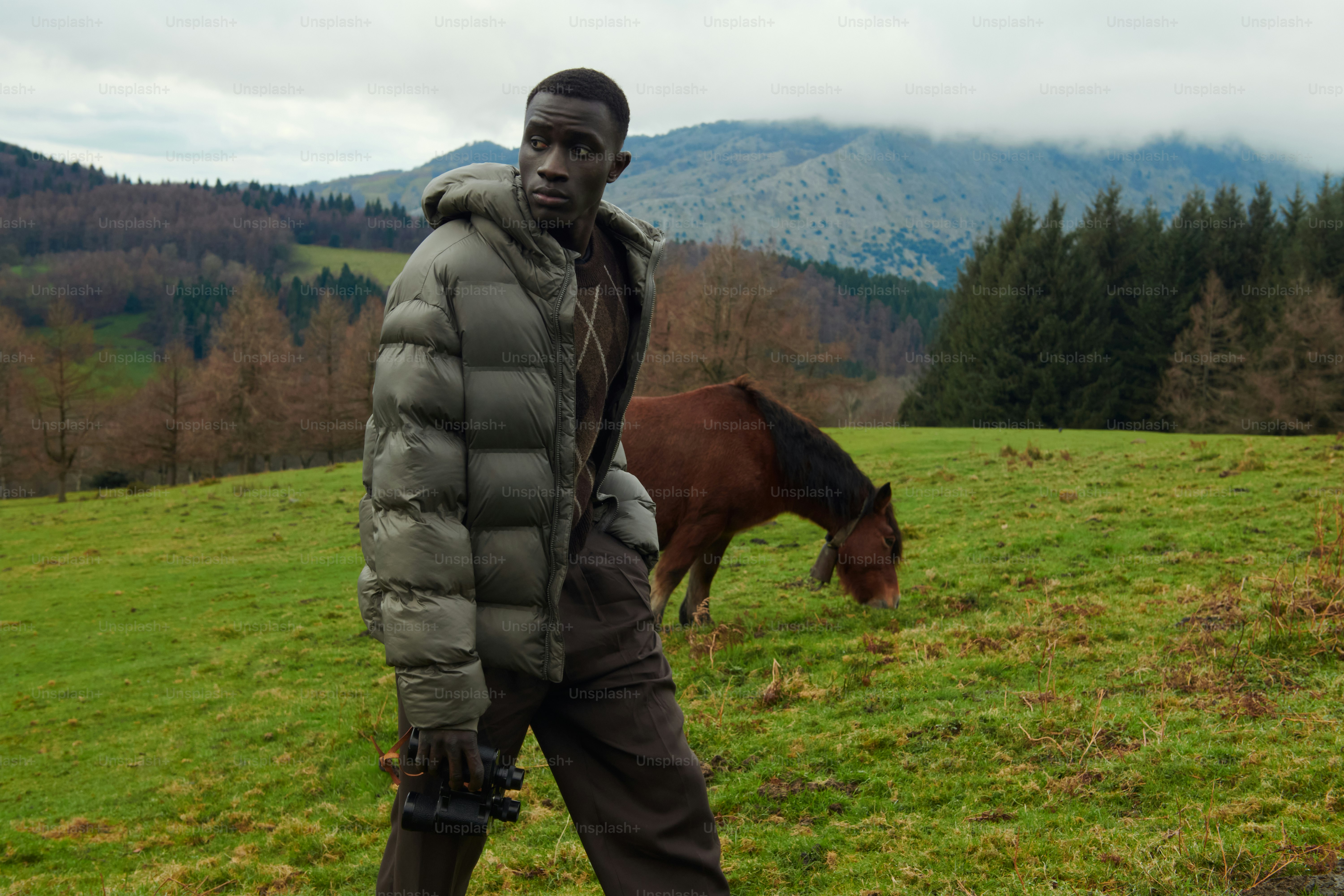 A man standing in a field next to a horse
