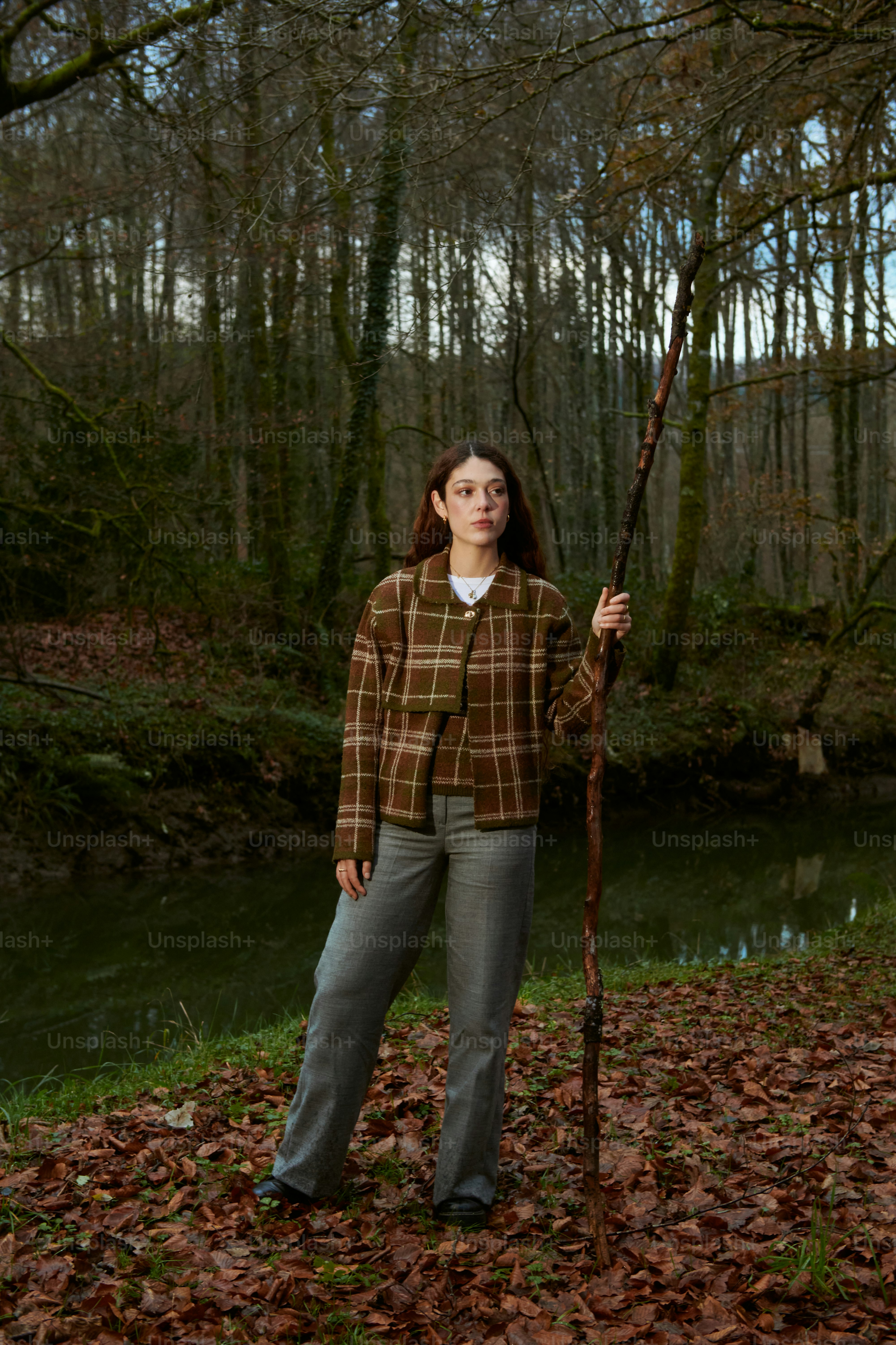 A woman holding a stick in a wooded area