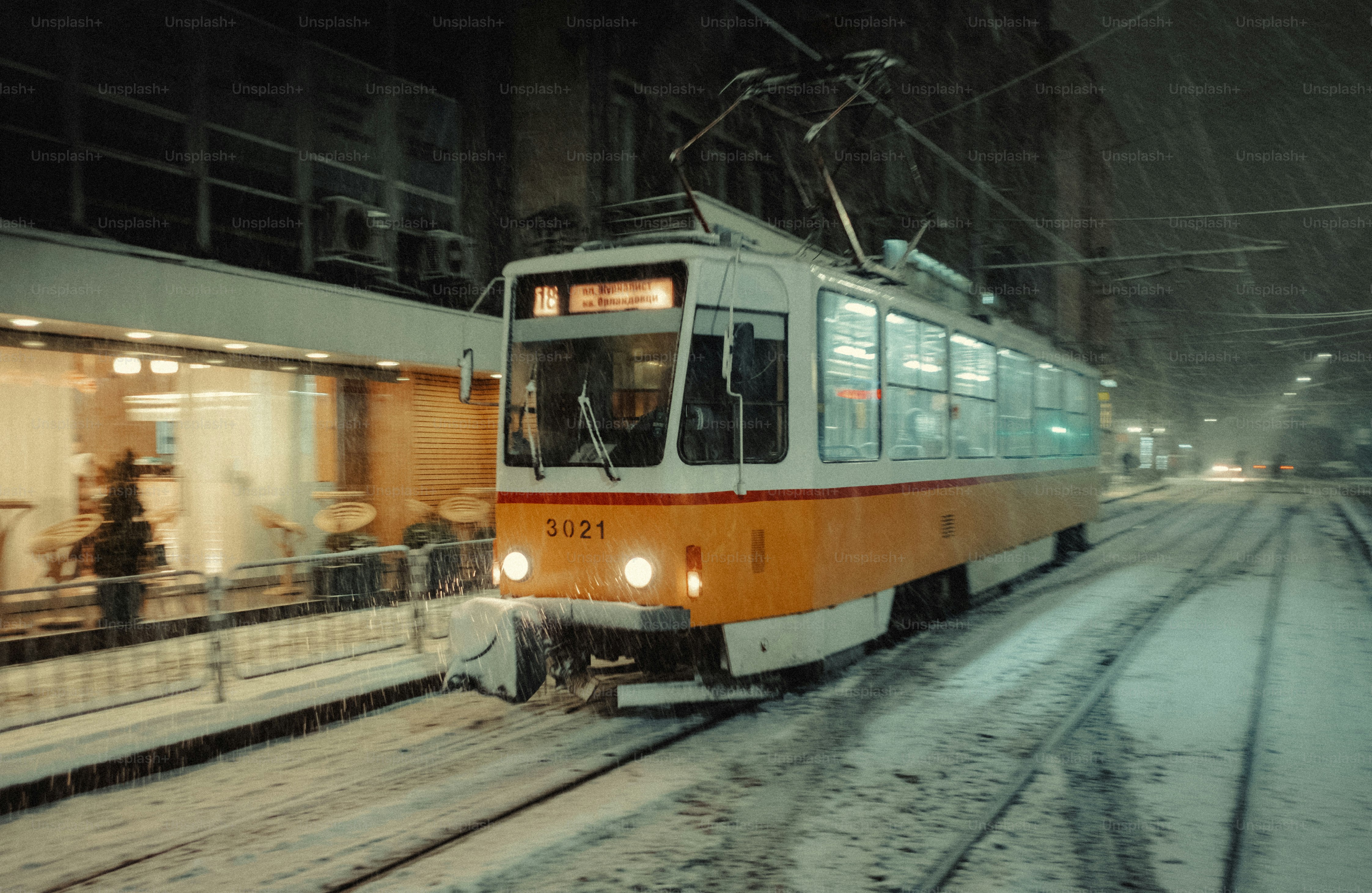 A yellow and white train traveling down train tracks