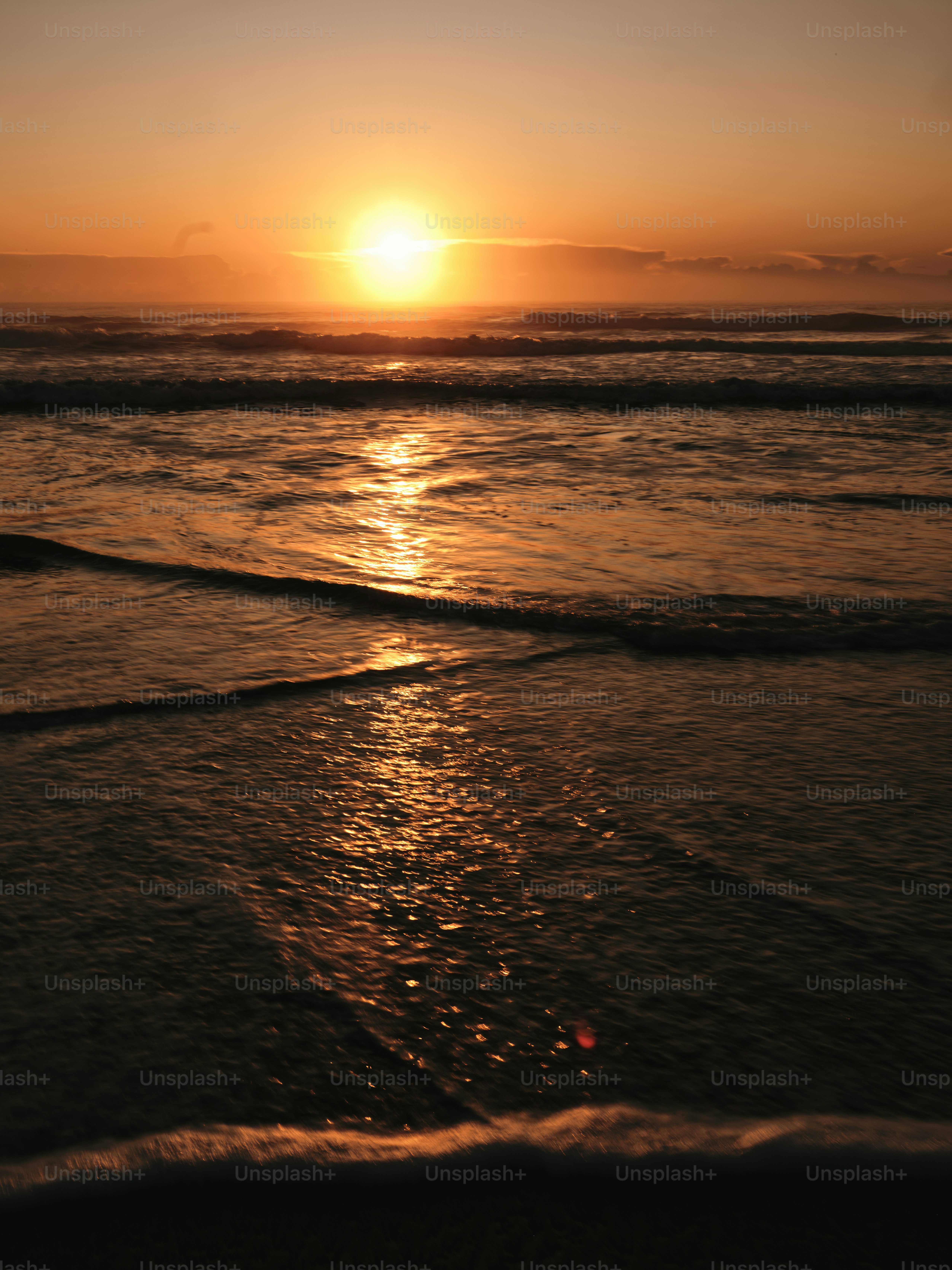 The sun is setting over the water at the beach
