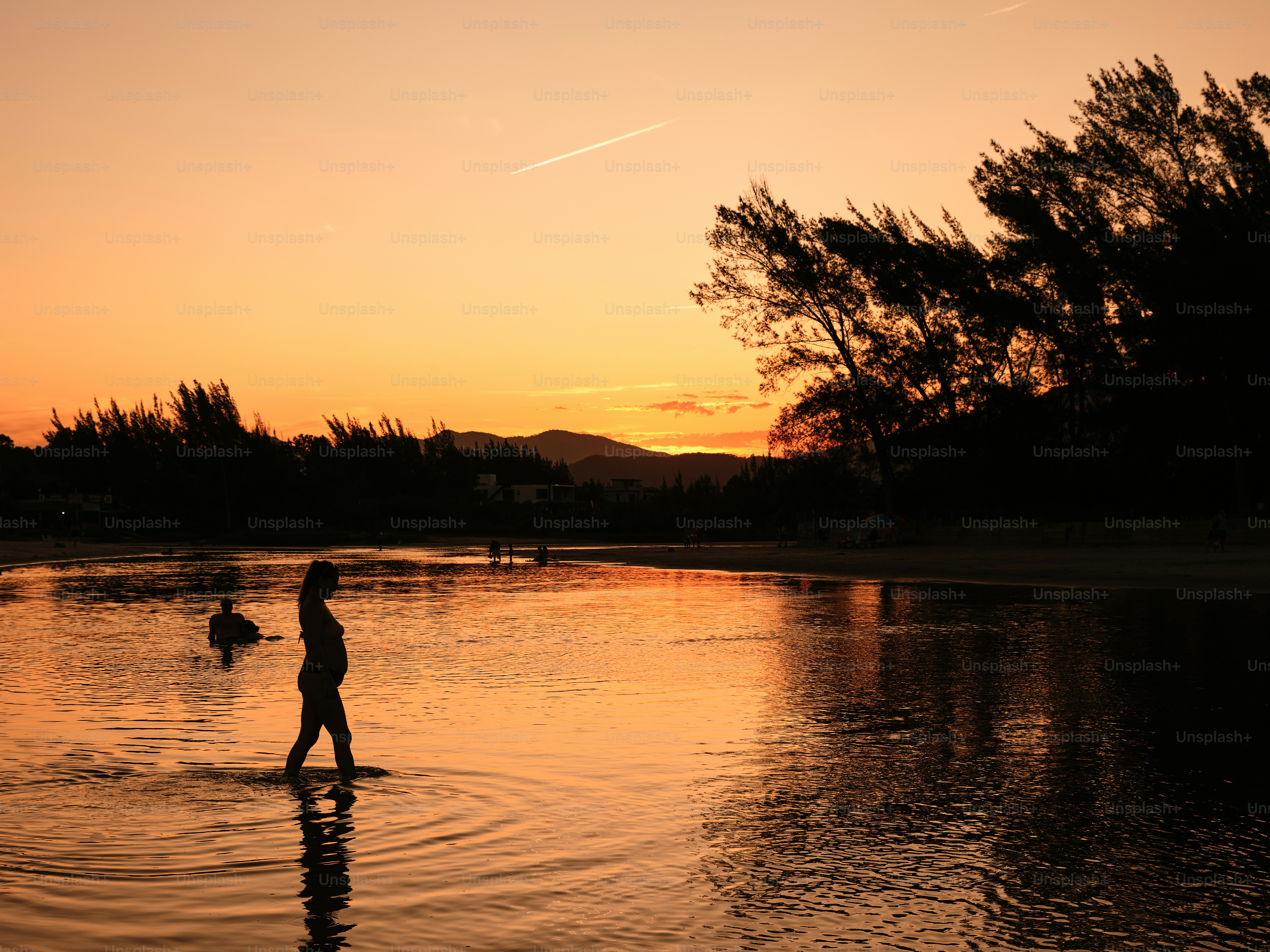 Uma pessoa andando na água ao pôr do sol