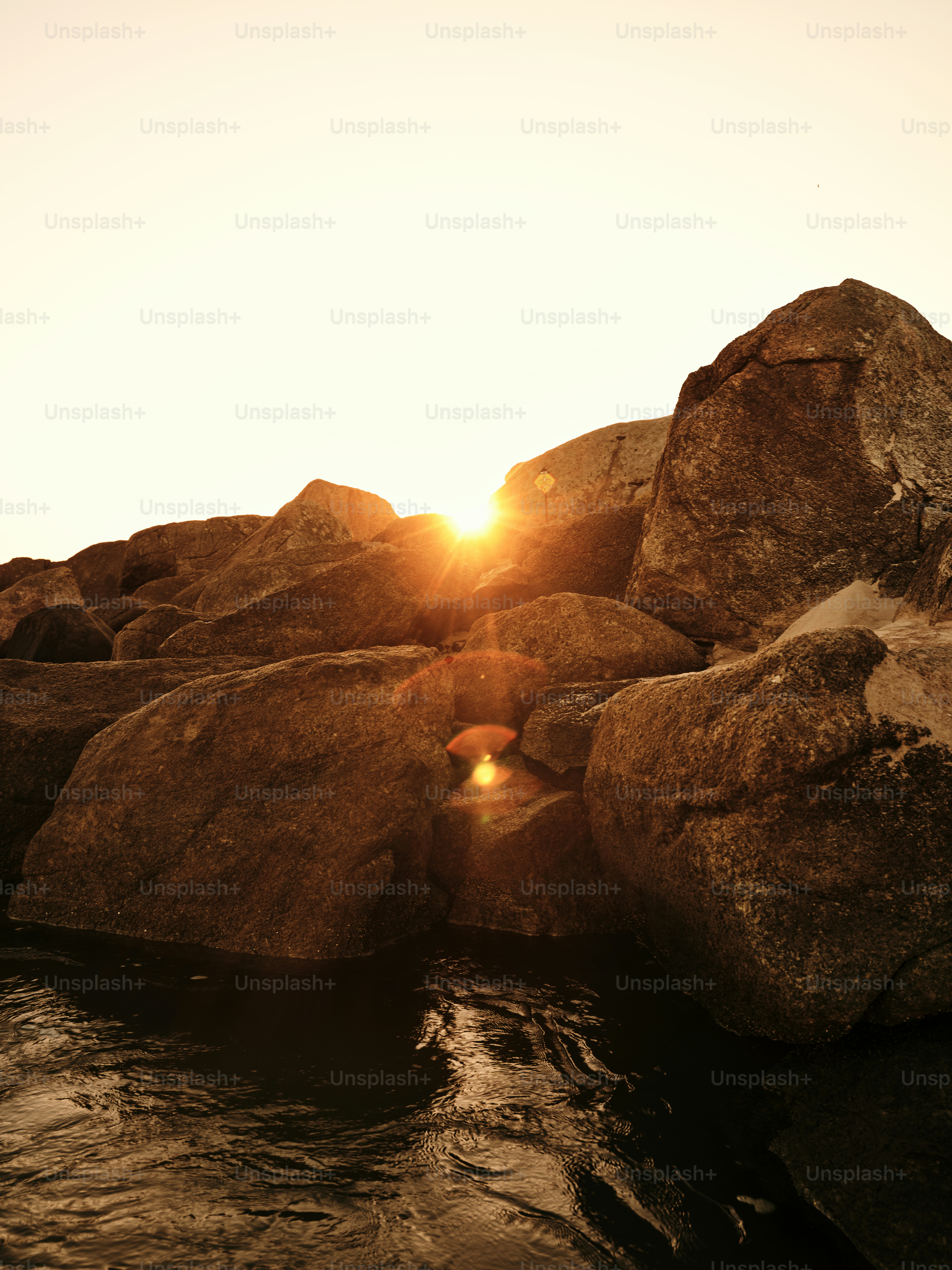 The sun is setting on the rocks in the water
