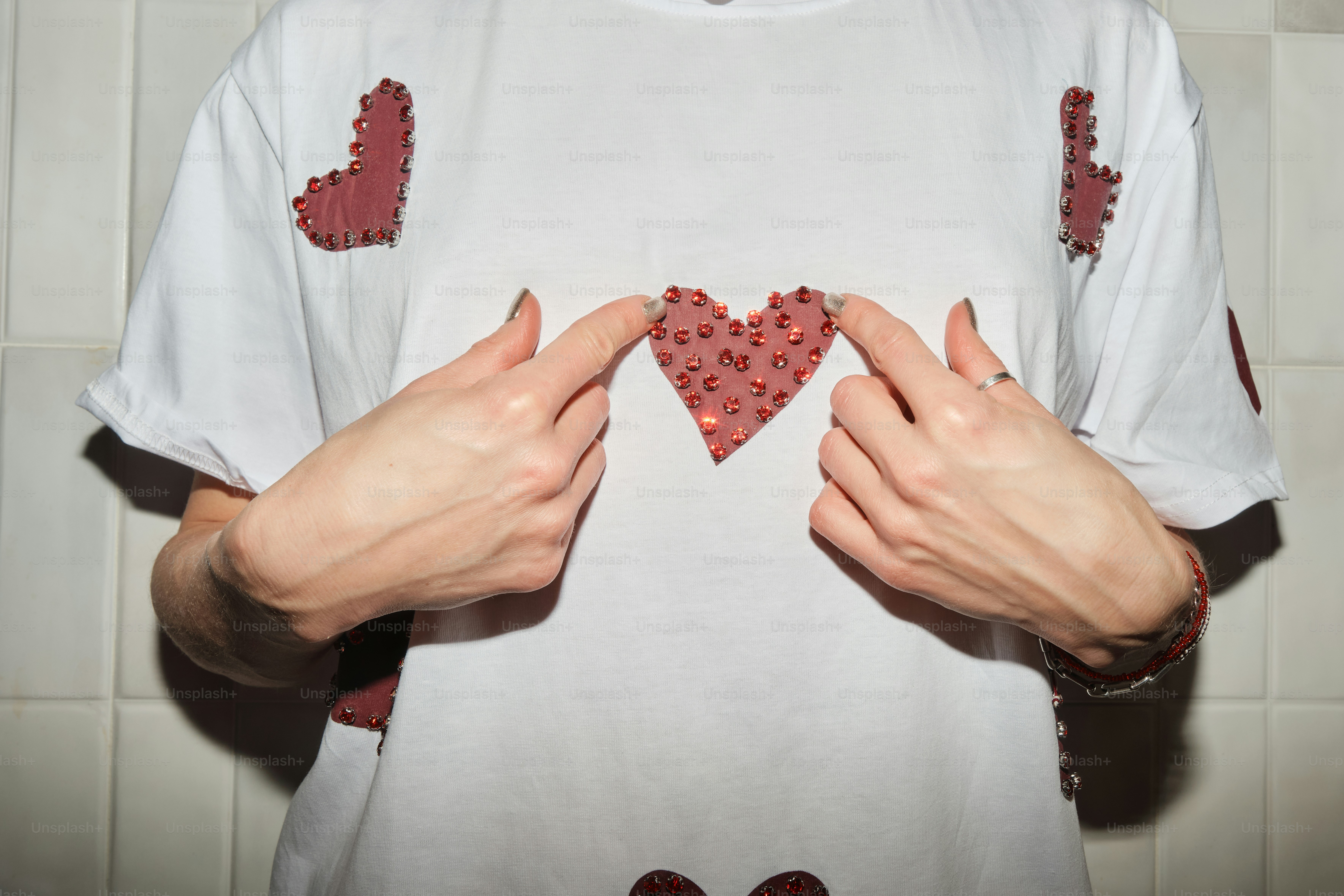 A woman holding her hands in front of her heart - shaped t - shirt