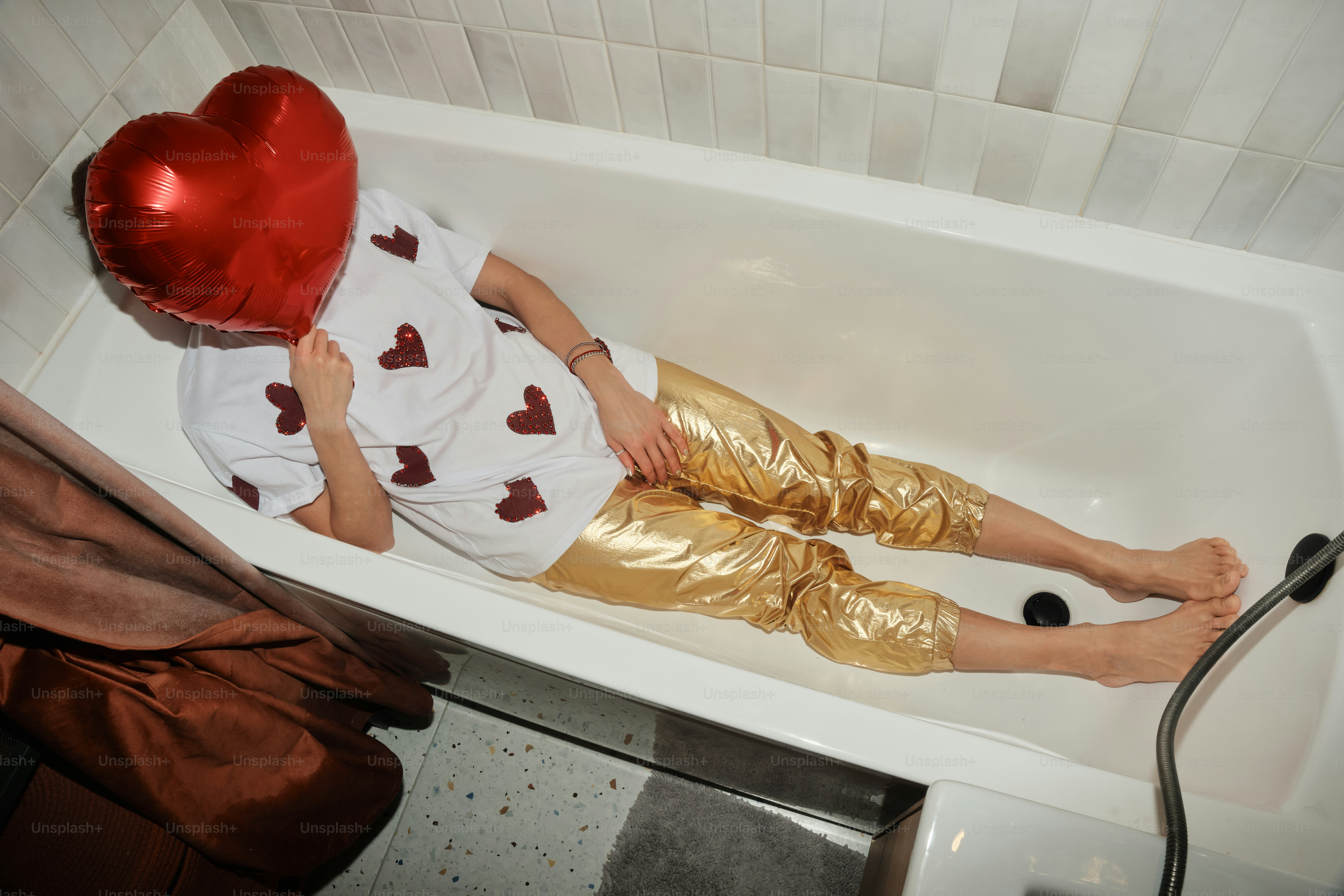 A person laying in a bath tub with a heart shaped balloon
