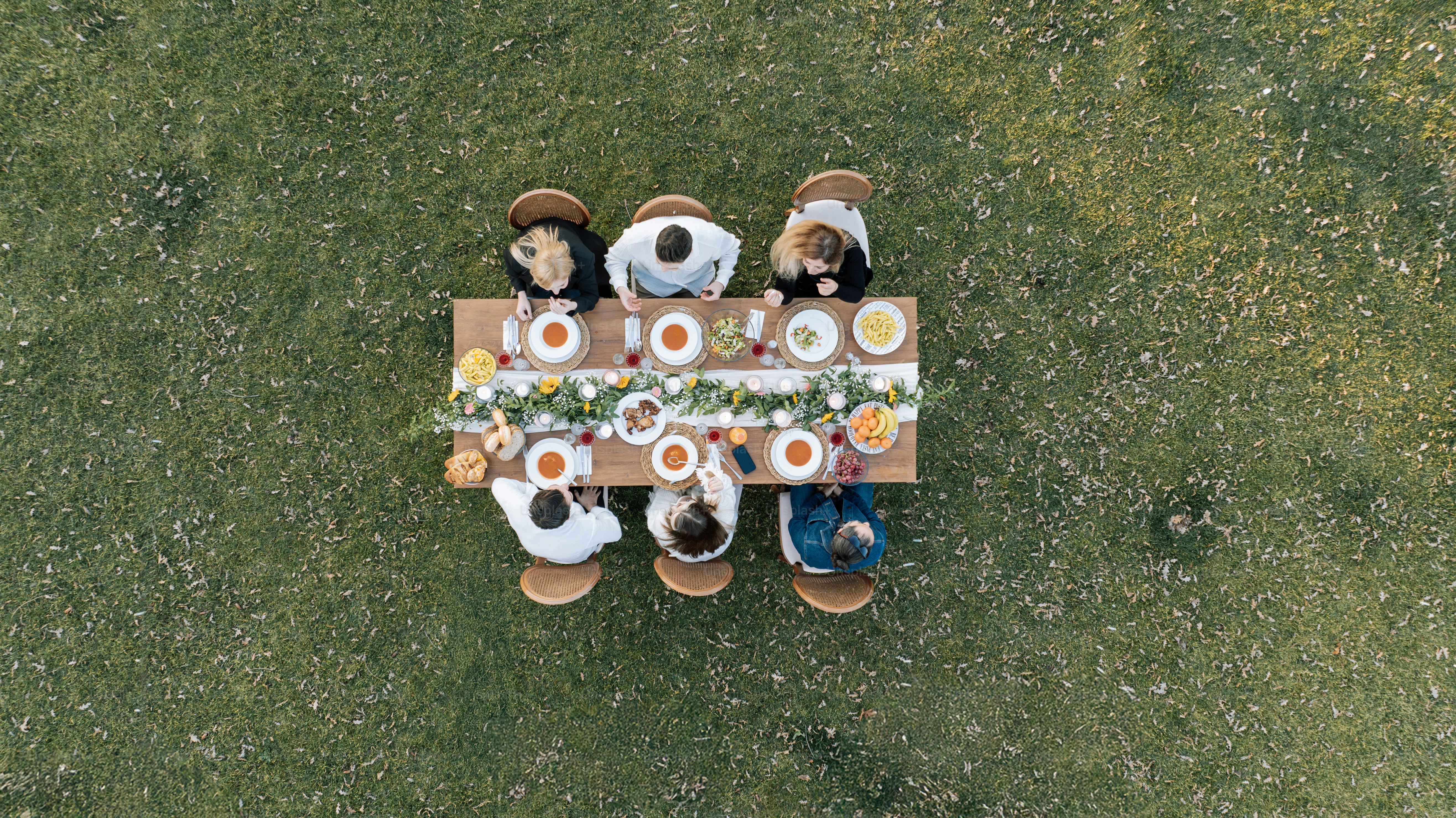 A group of people sitting around a table with wine glasses photo – Food ...