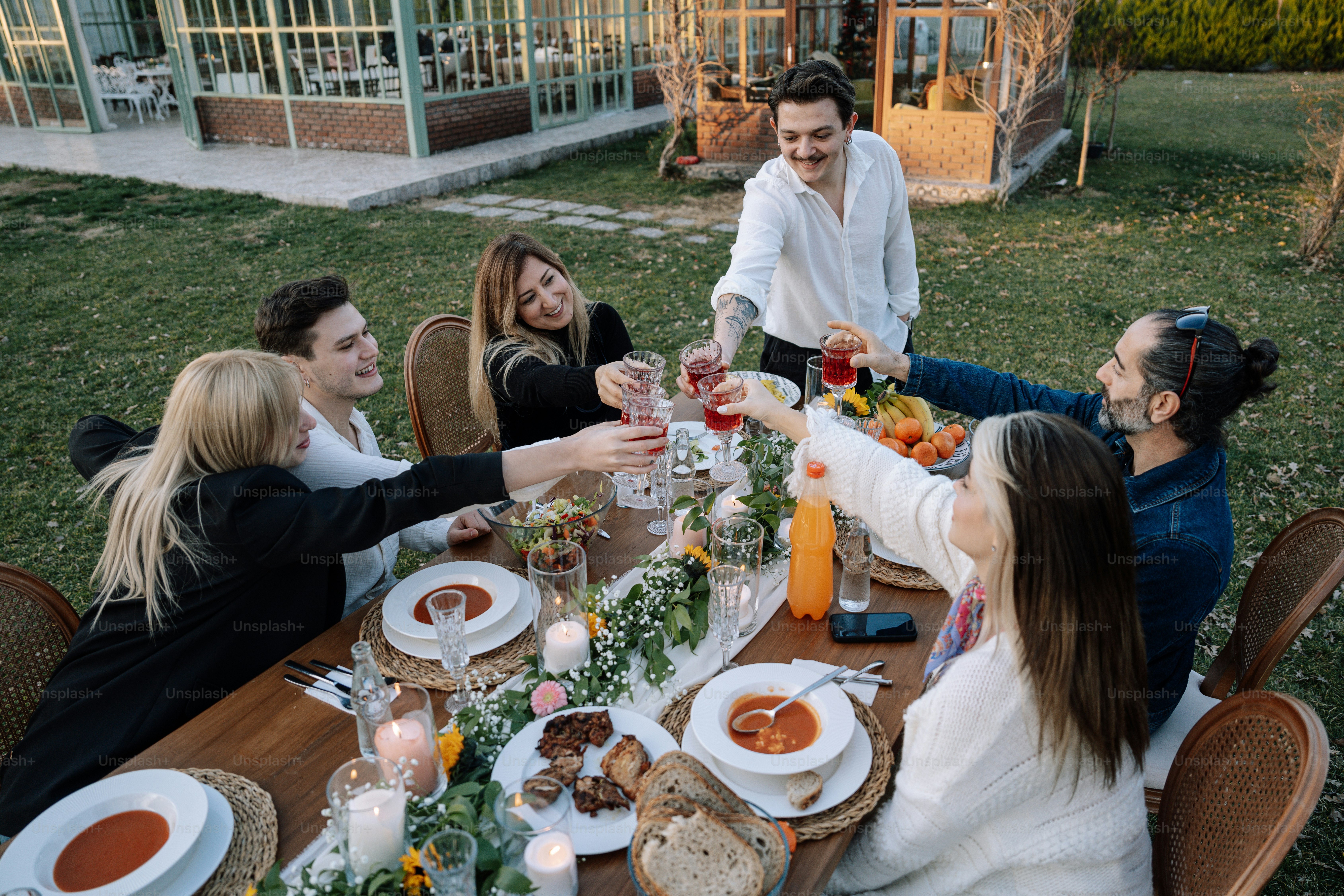 A group of people sitting around a table with food photo – Dinner Image ...