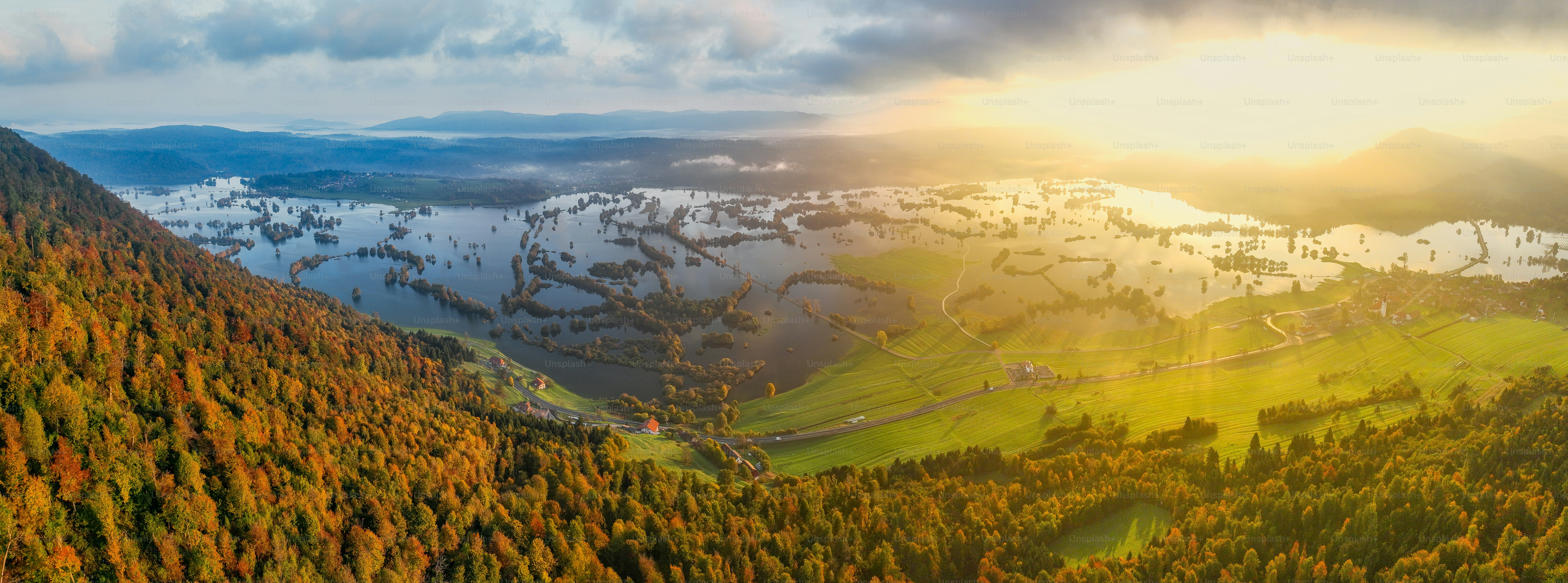 The sun shines through the clouds over the mountains