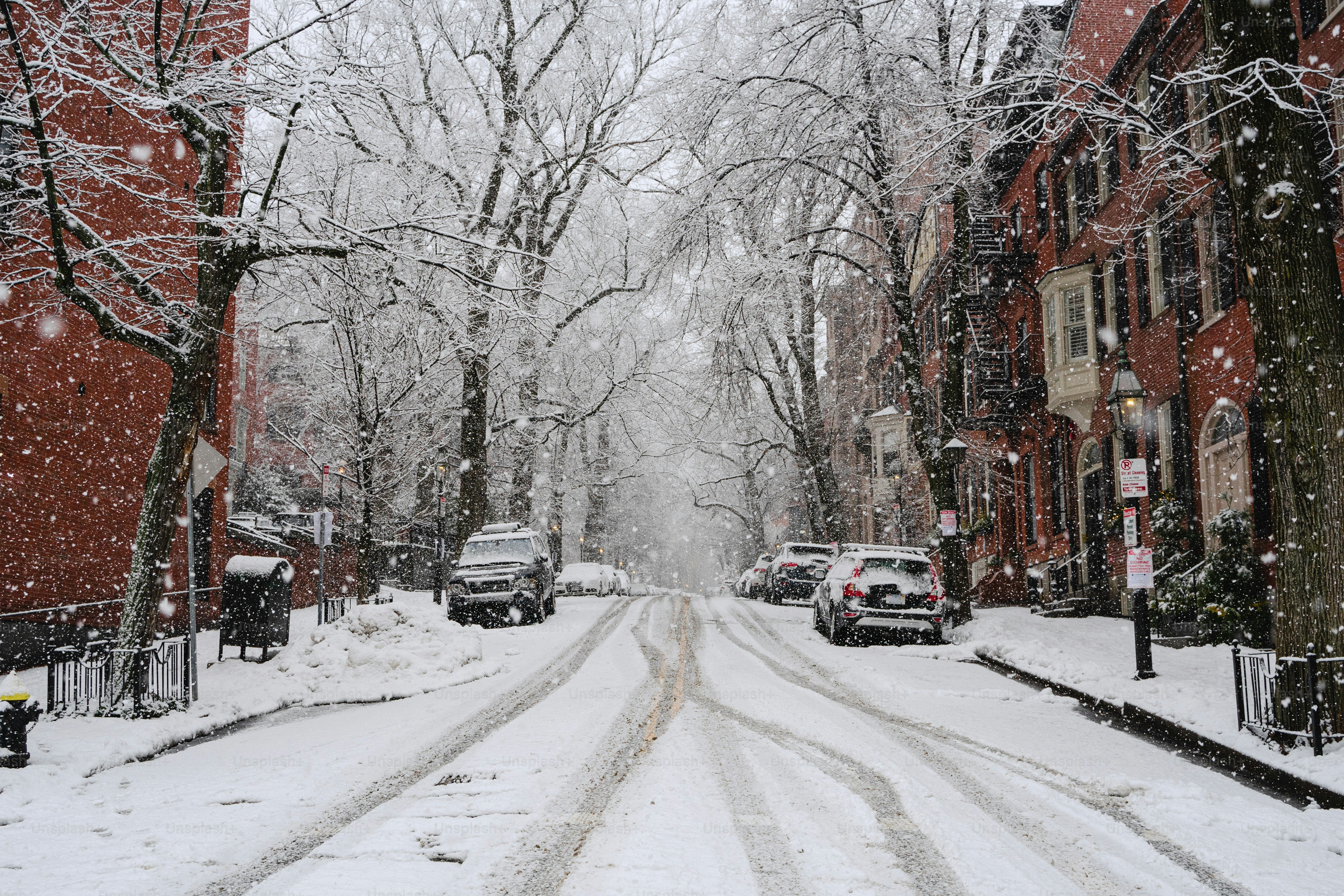 A snowy street with cars parked on the side of it