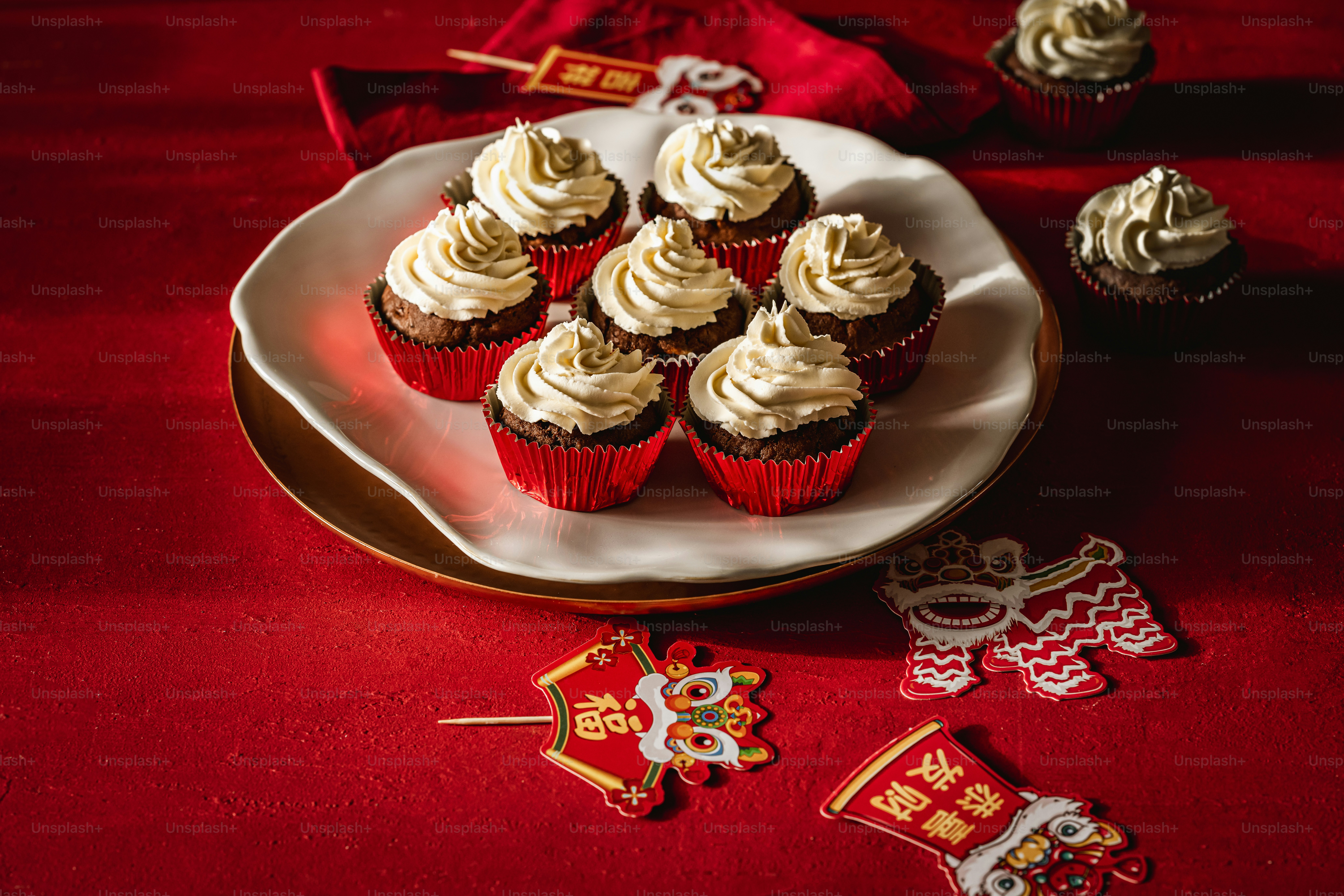 A plate of cupcakes on a red table cloth