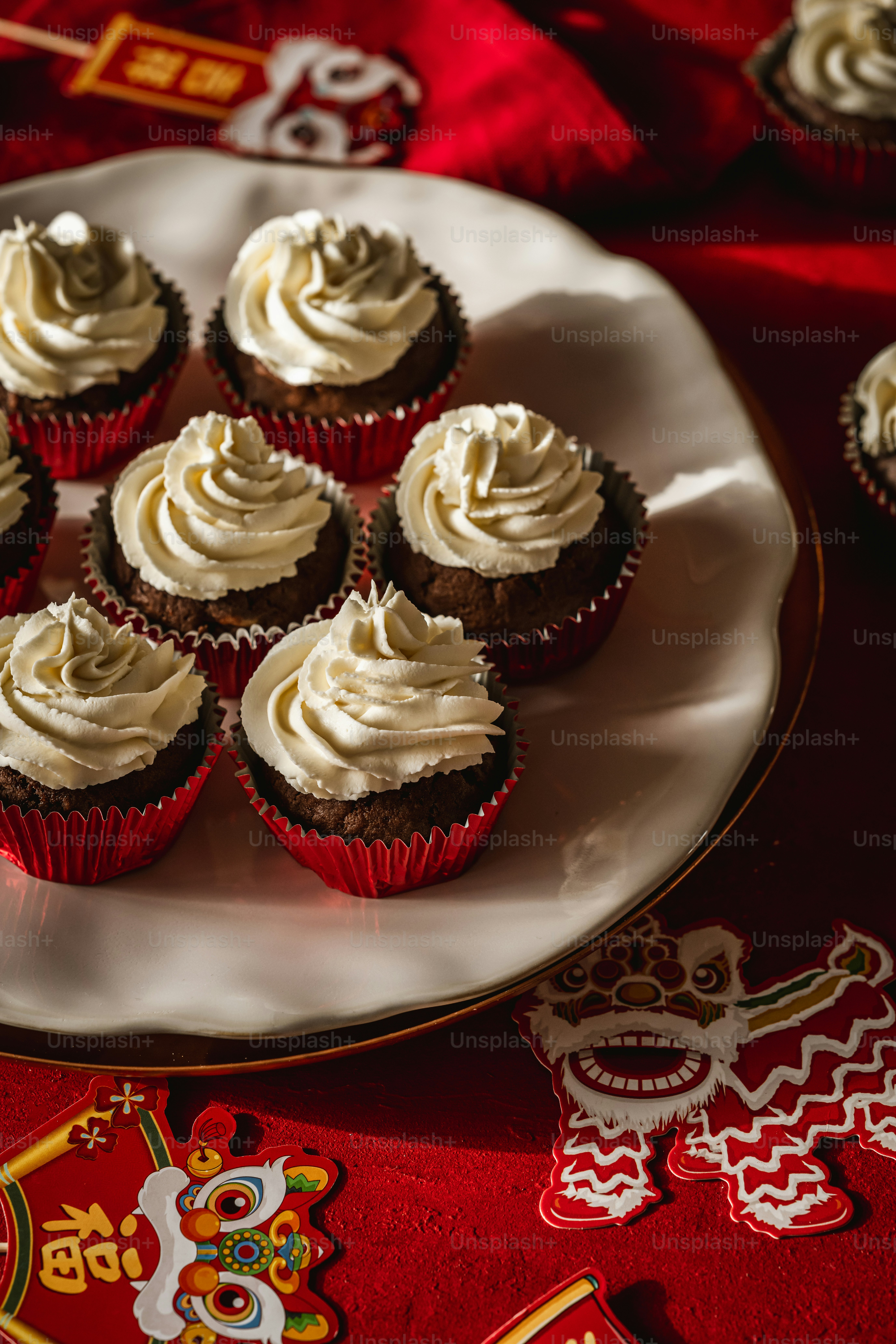 A plate of cupcakes on a red table cloth