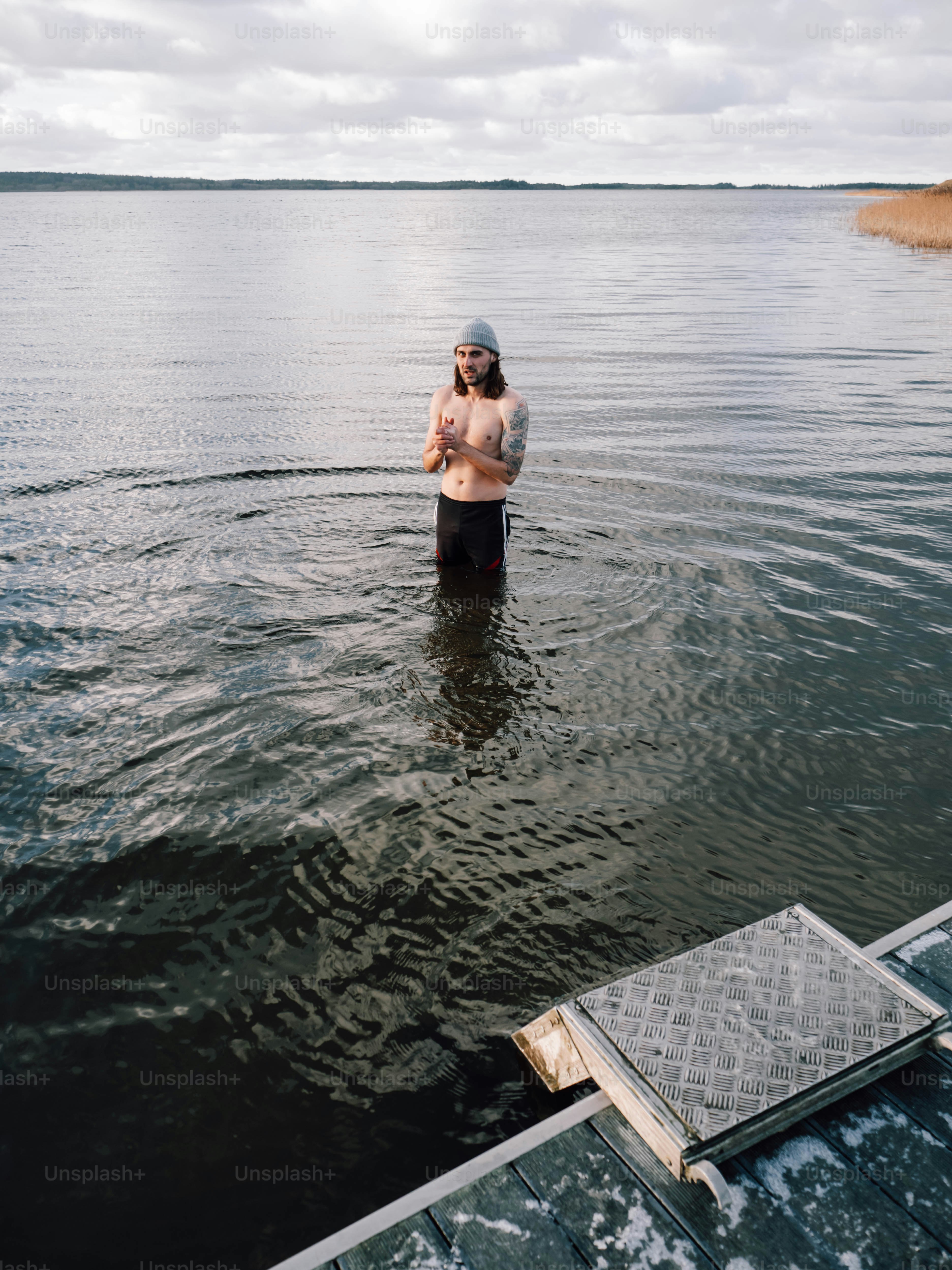 A man standing in the water next to a boat photo – Winter Image on Unsplash