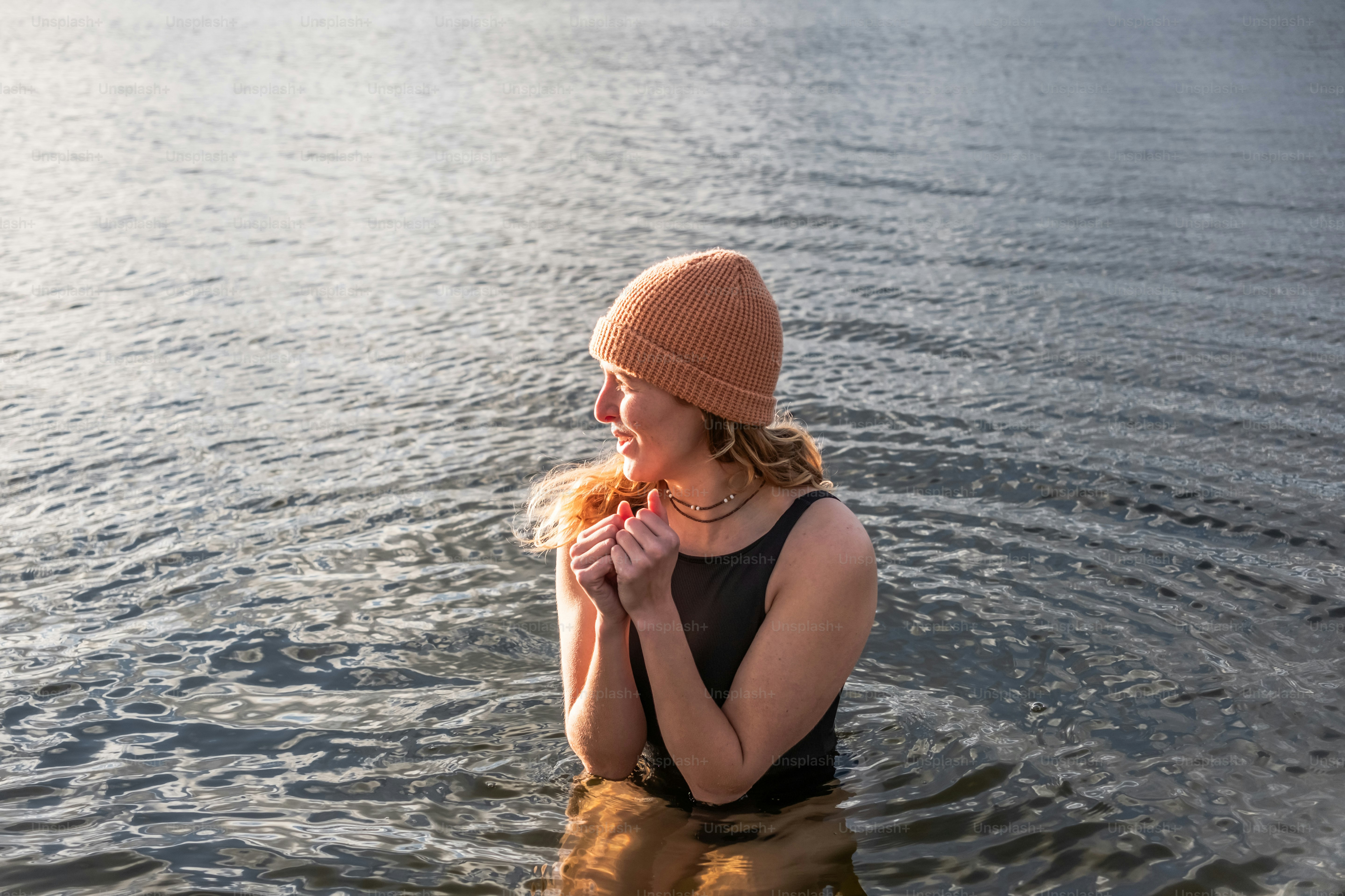 A woman standing in the water eating a donut