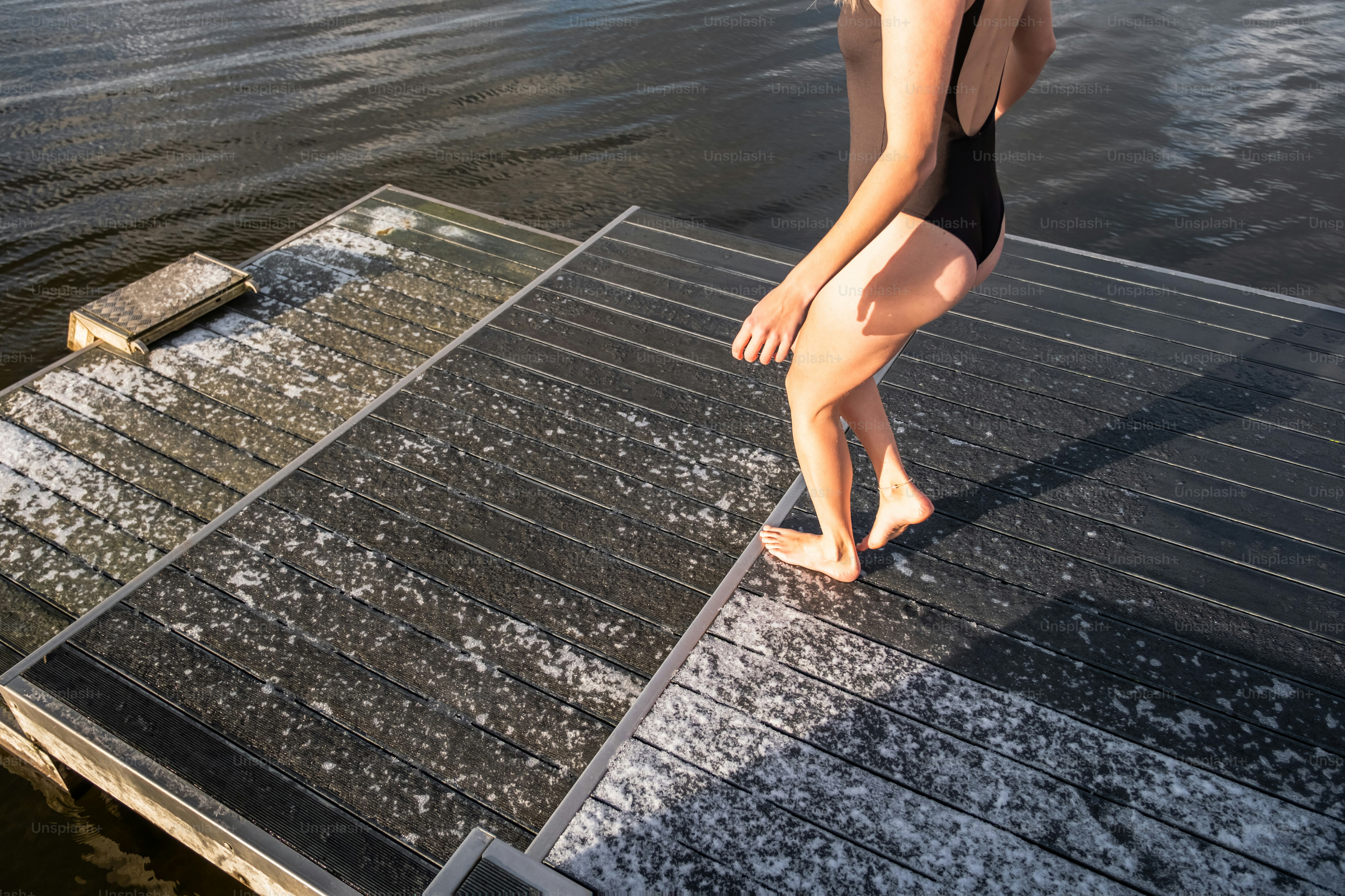 A woman standing on a dock next to a body of water