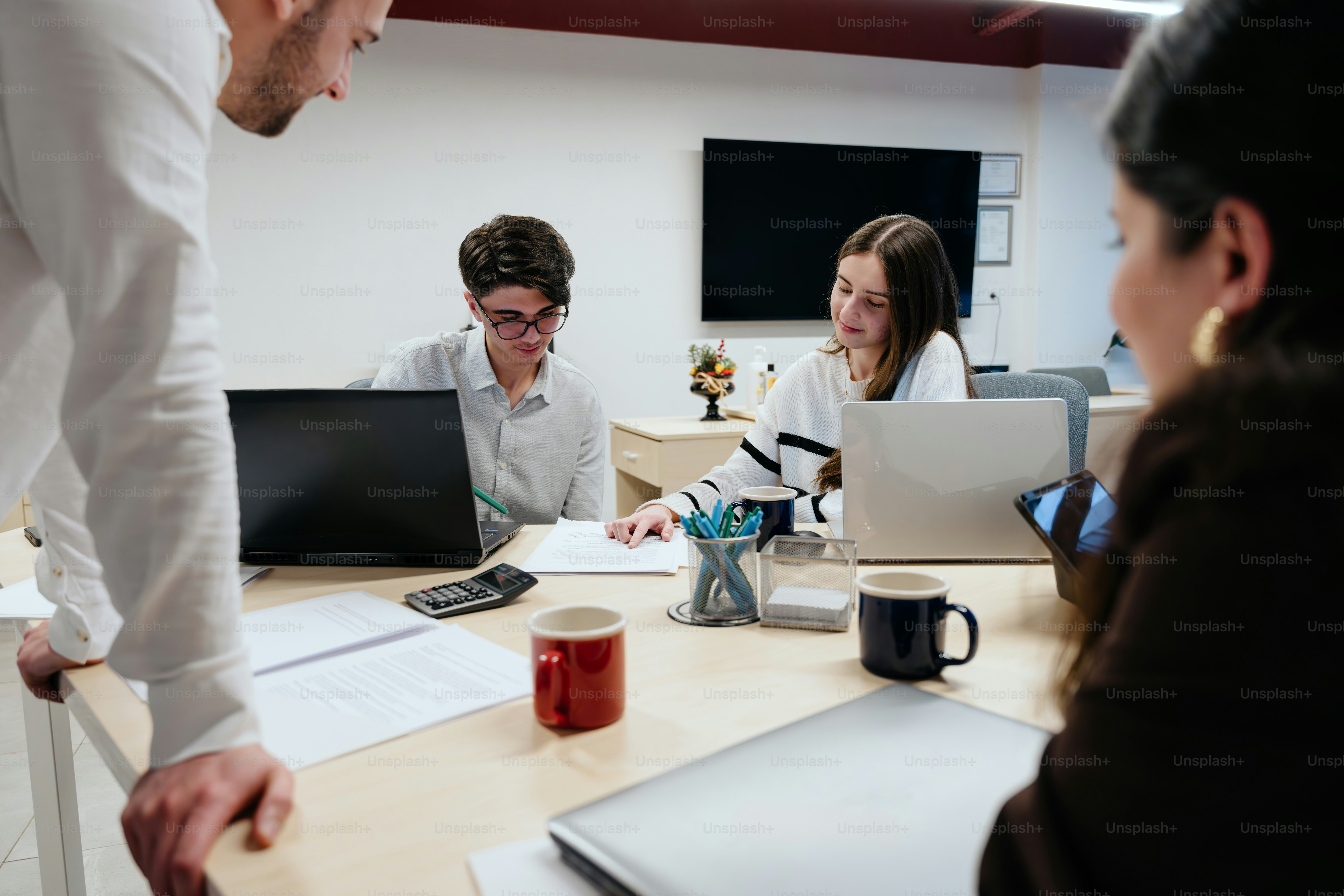 A group of people sitting around a table with laptops photo – Office ...