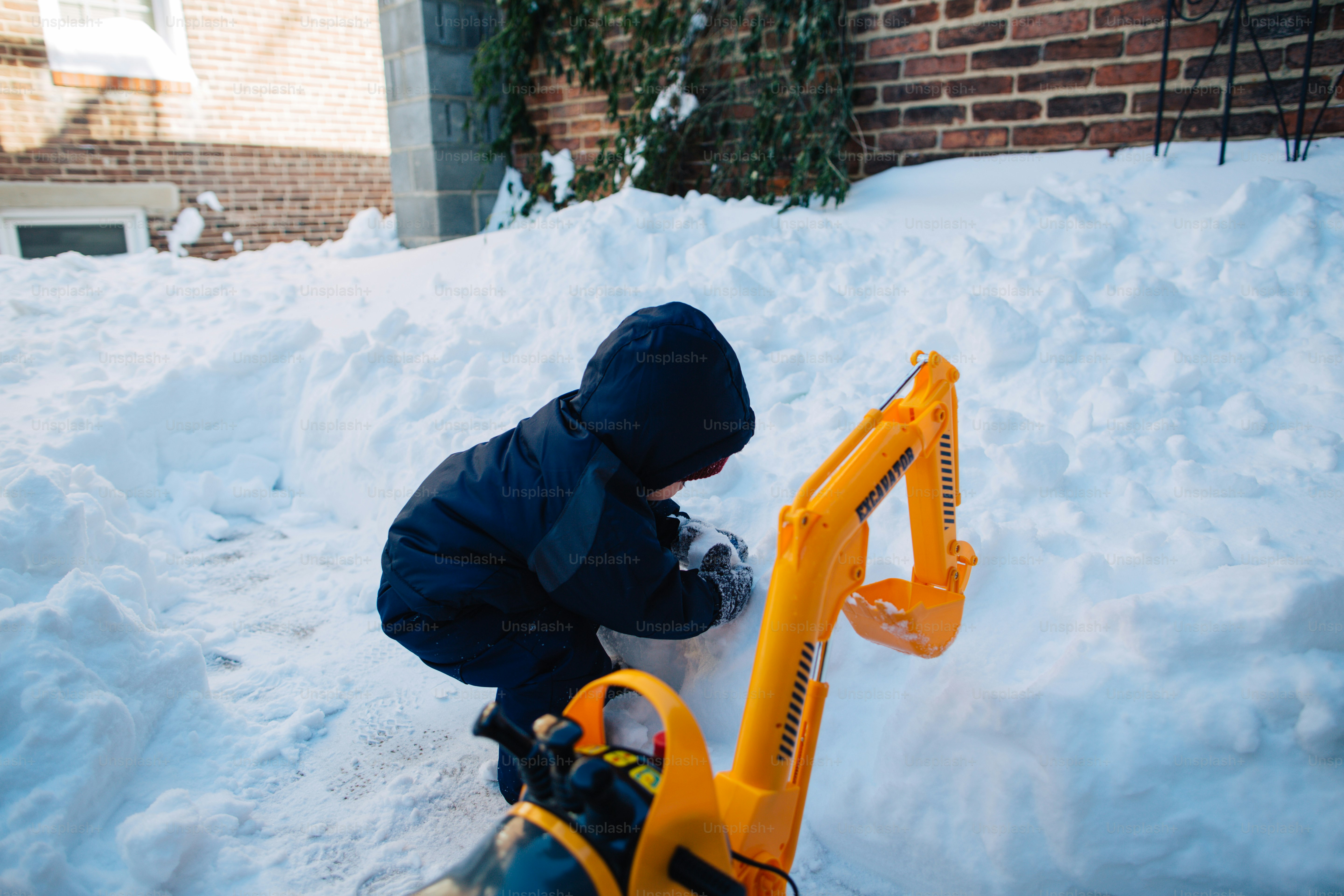 A young boy playing in the snow with a tractor
