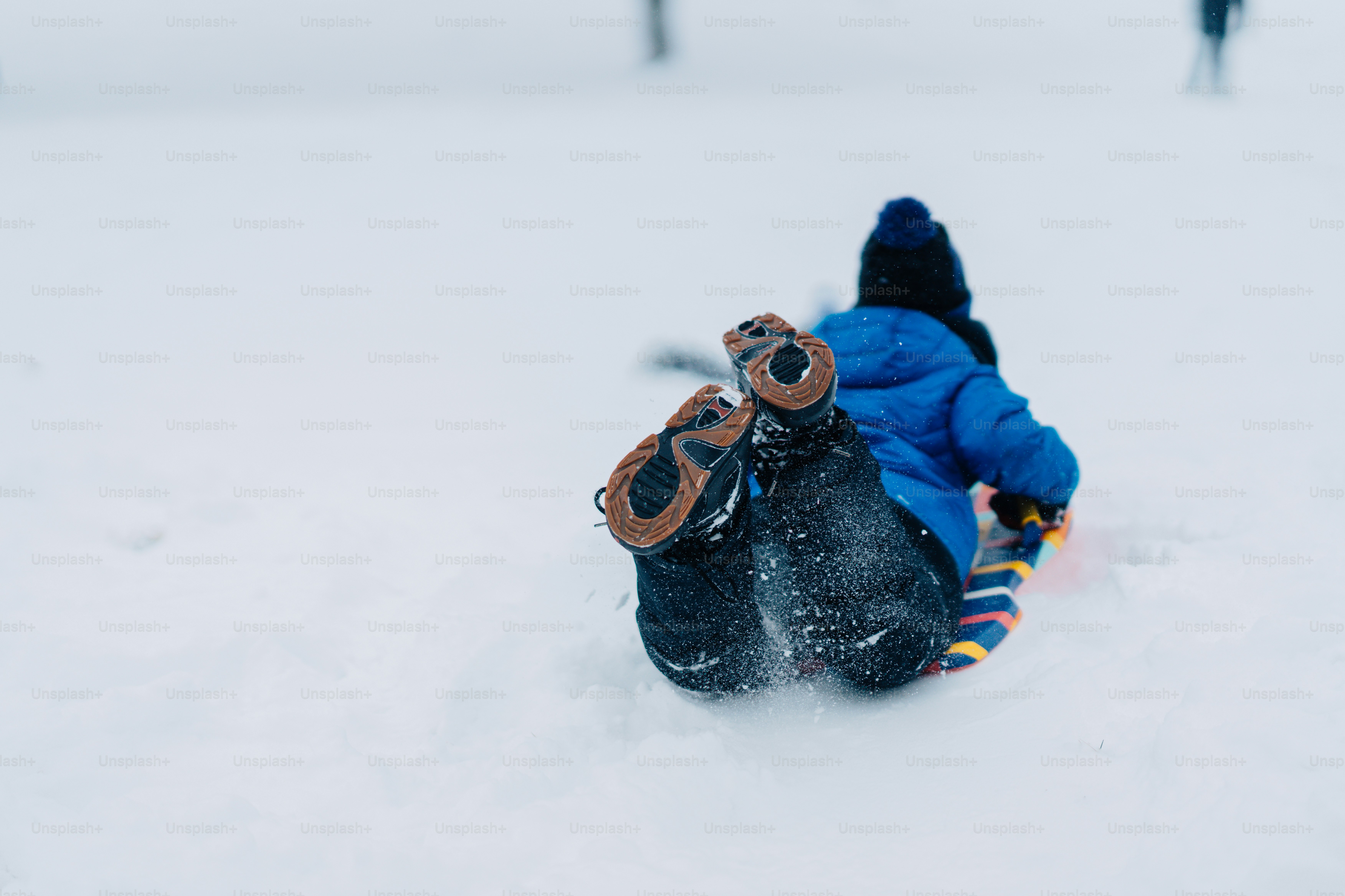 A young child sliding down a hill on a snowboard