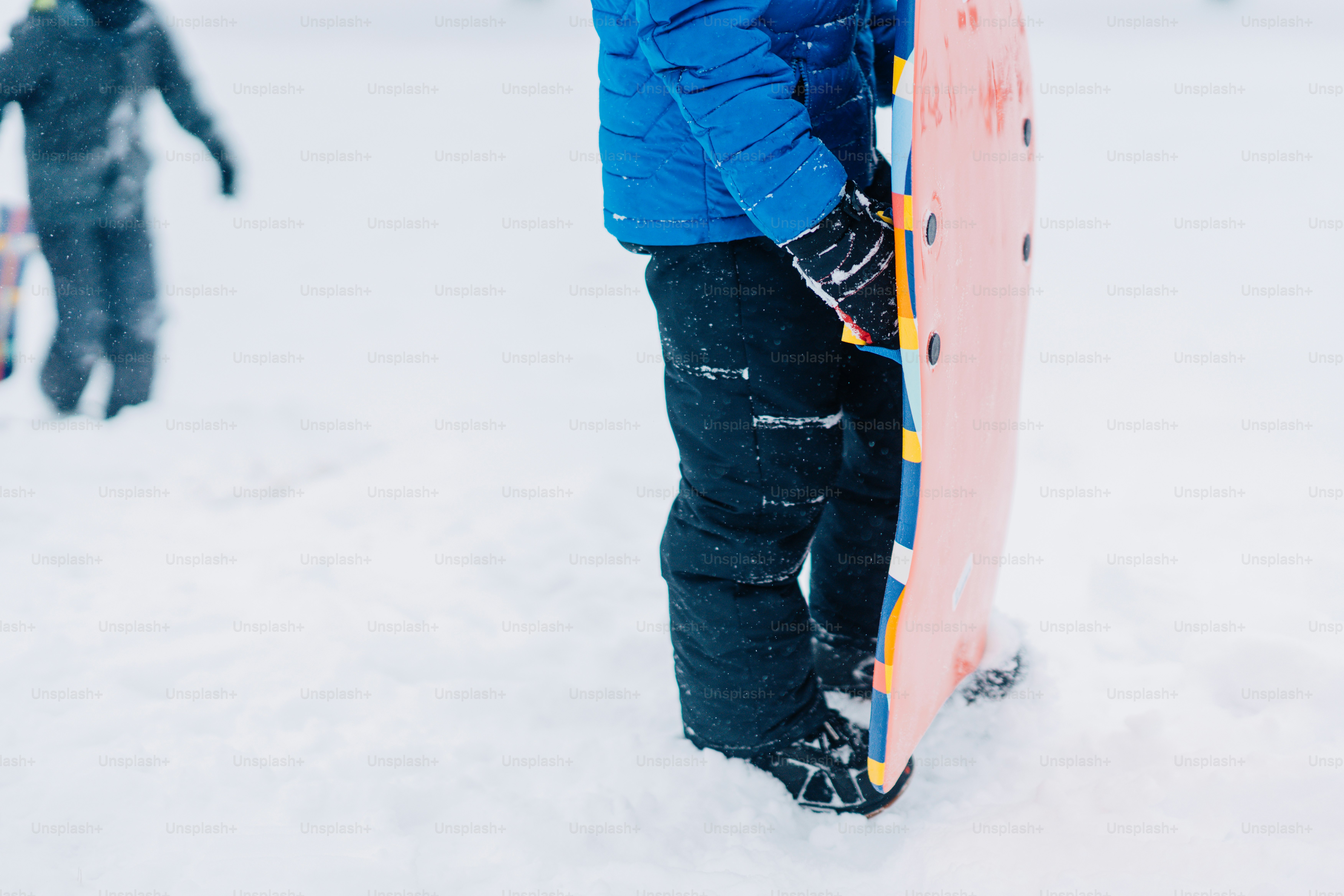 A person standing in the snow holding a snowboard