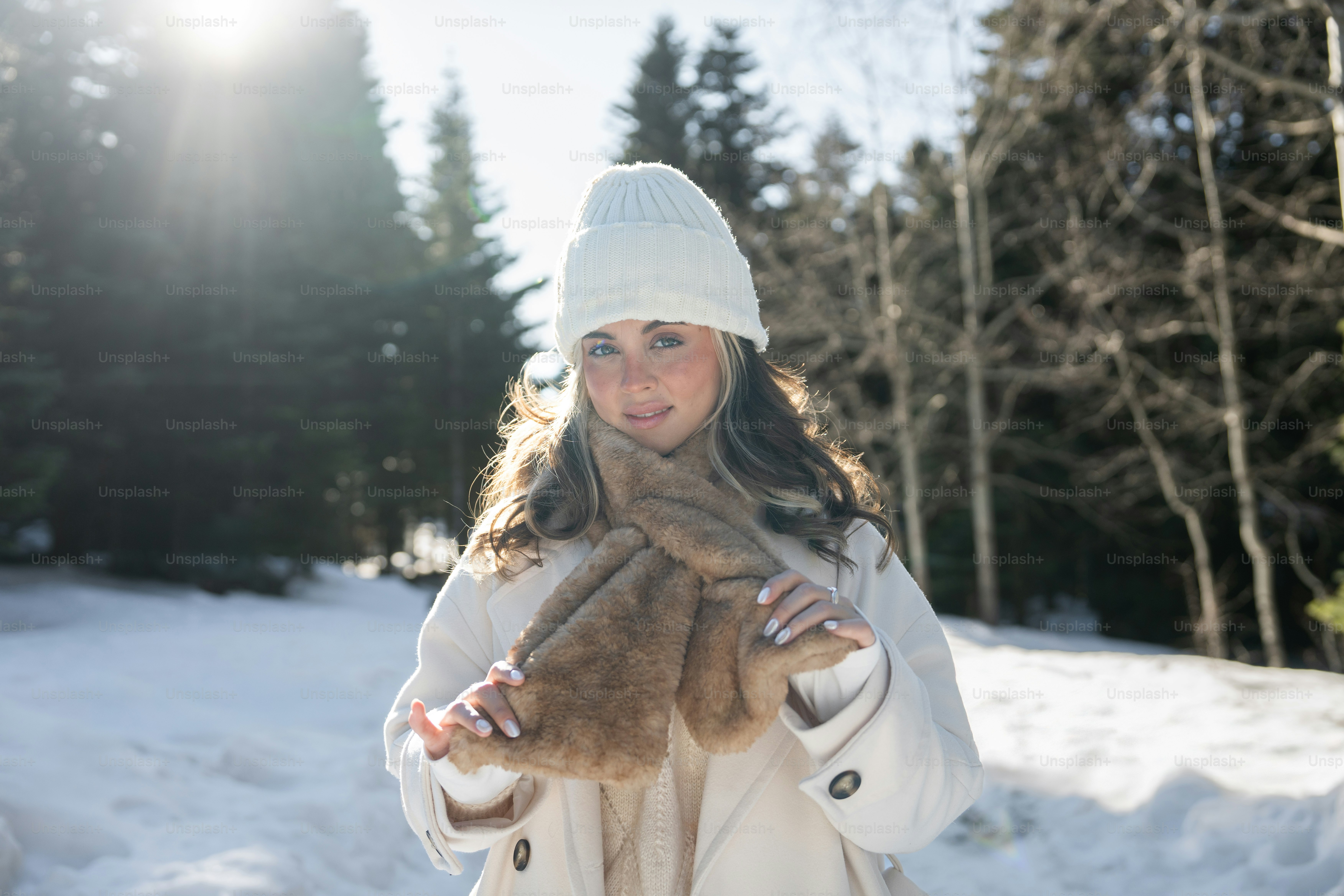 A woman in a white coat holding a cat in the snow