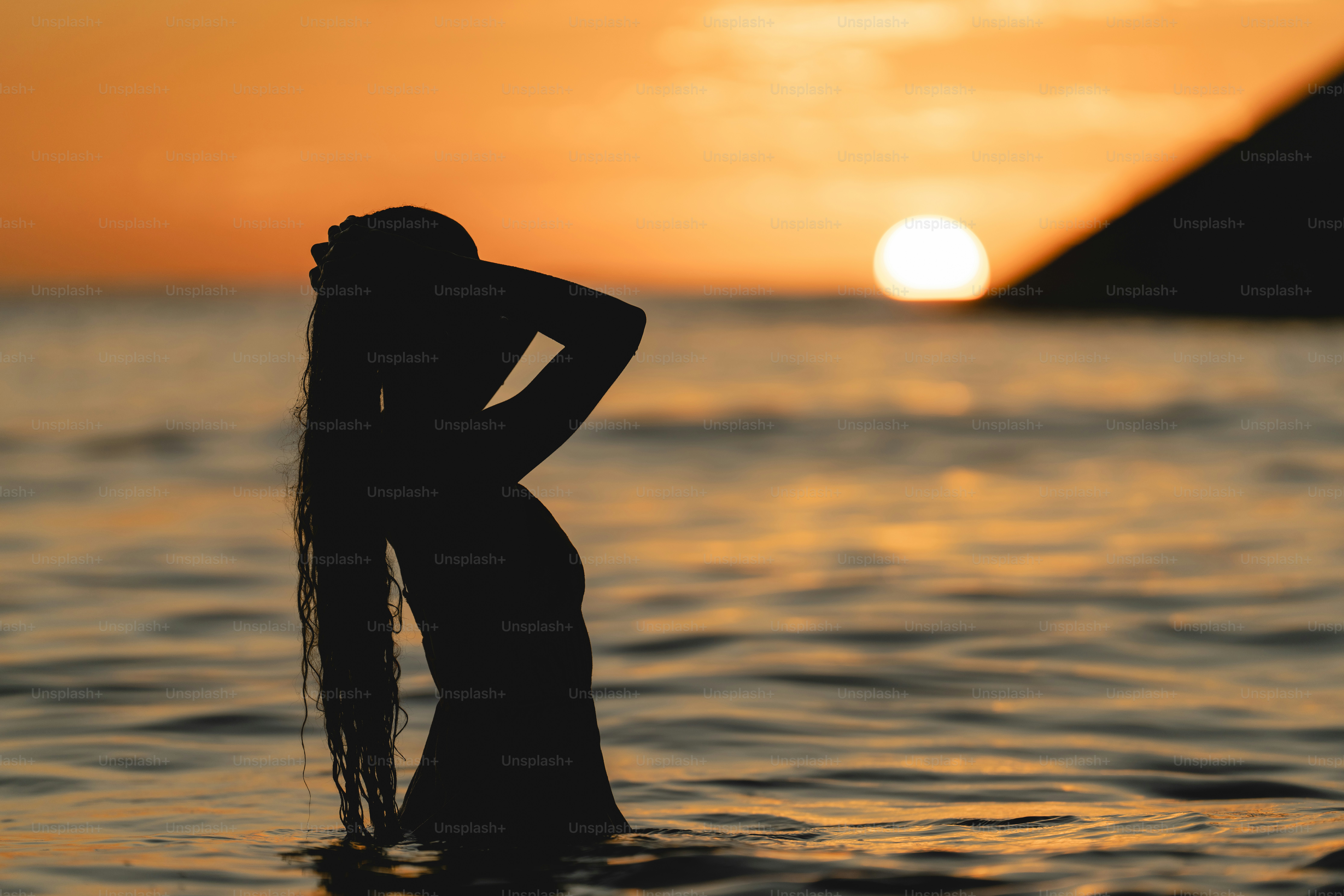 Uma mulher em pé na água ao pôr do sol