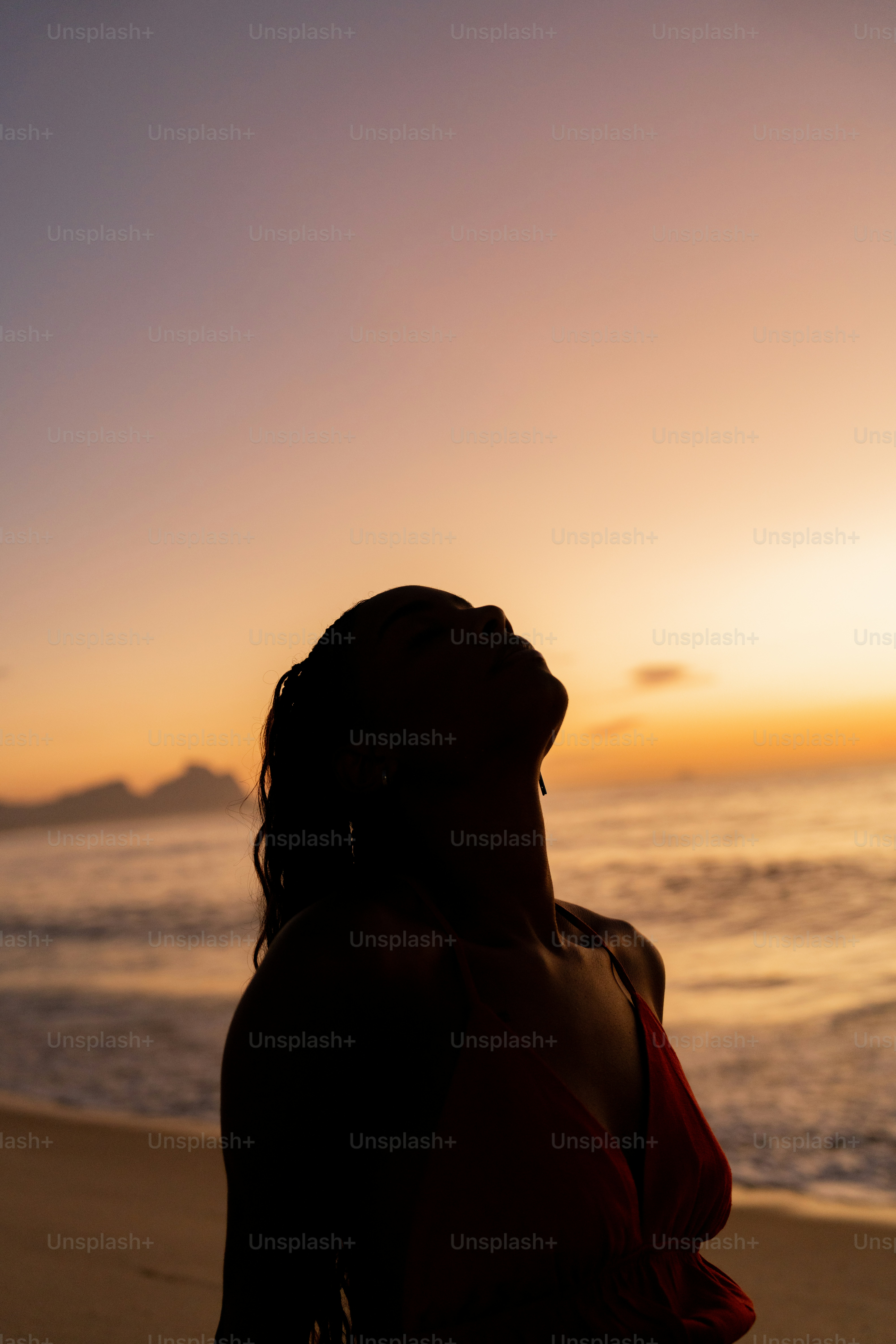 Uma mulher sentada na praia assistindo ao pôr do sol