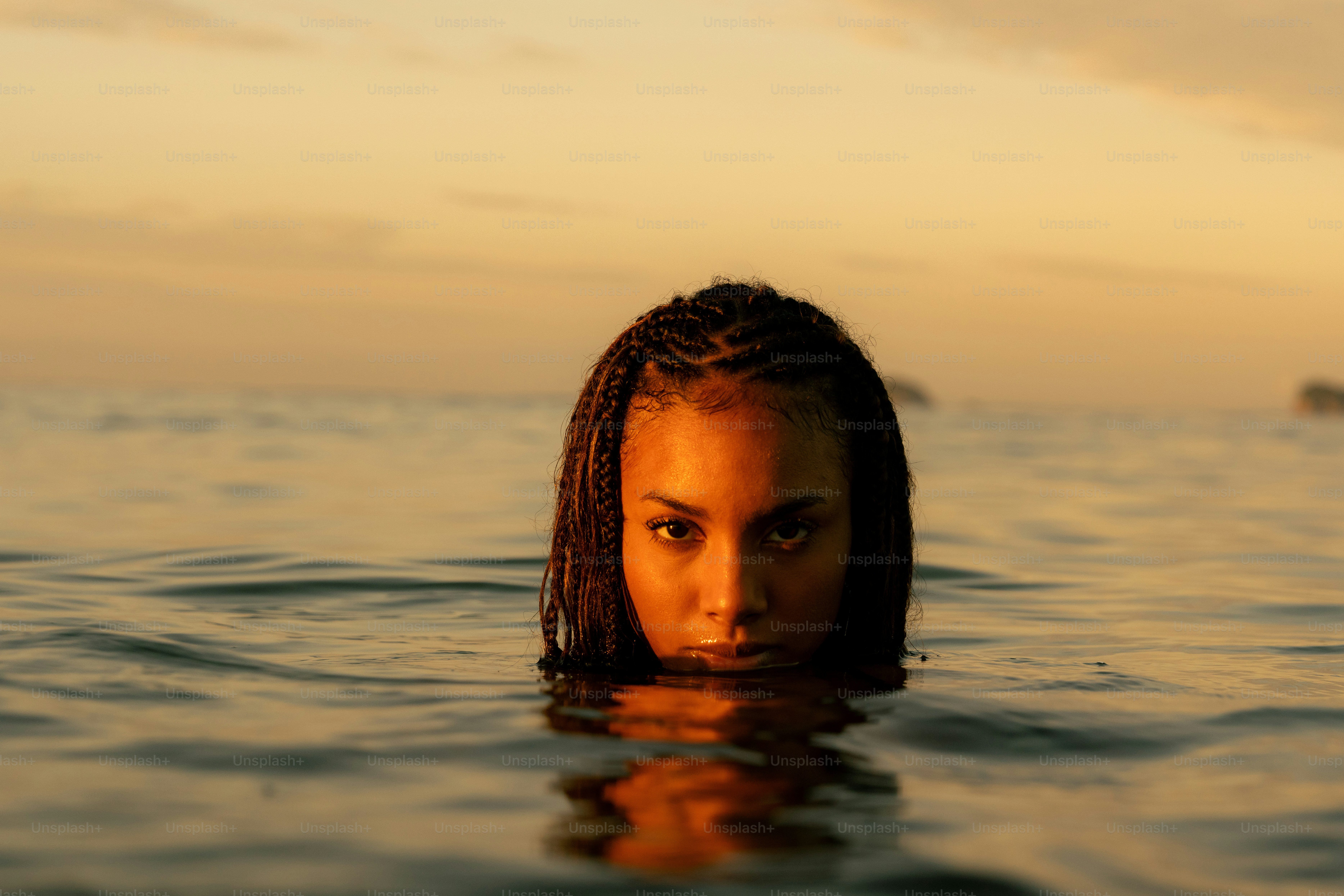 A woman swimming in the ocean at sunset