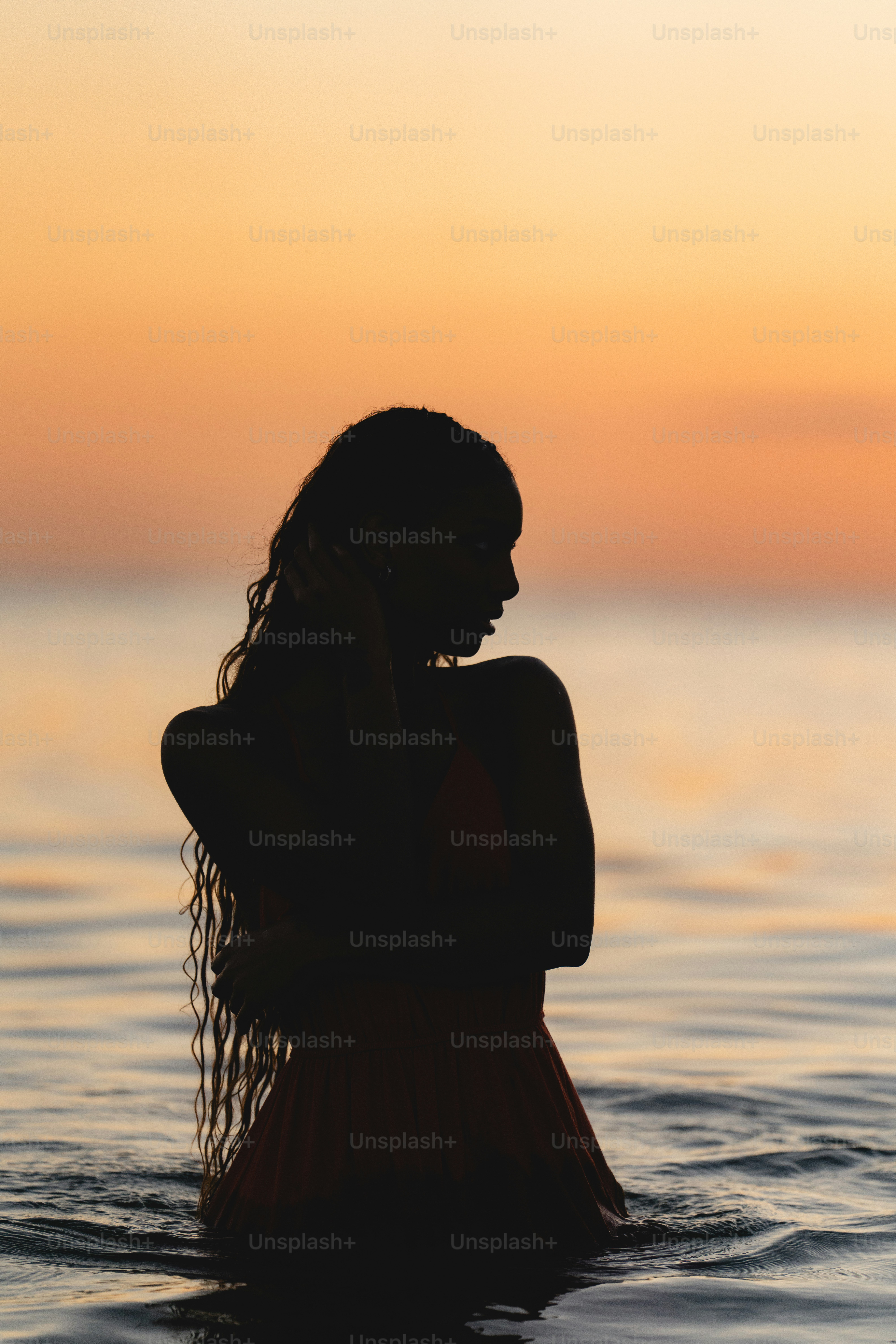 Uma mulher em pé na água ao pôr do sol